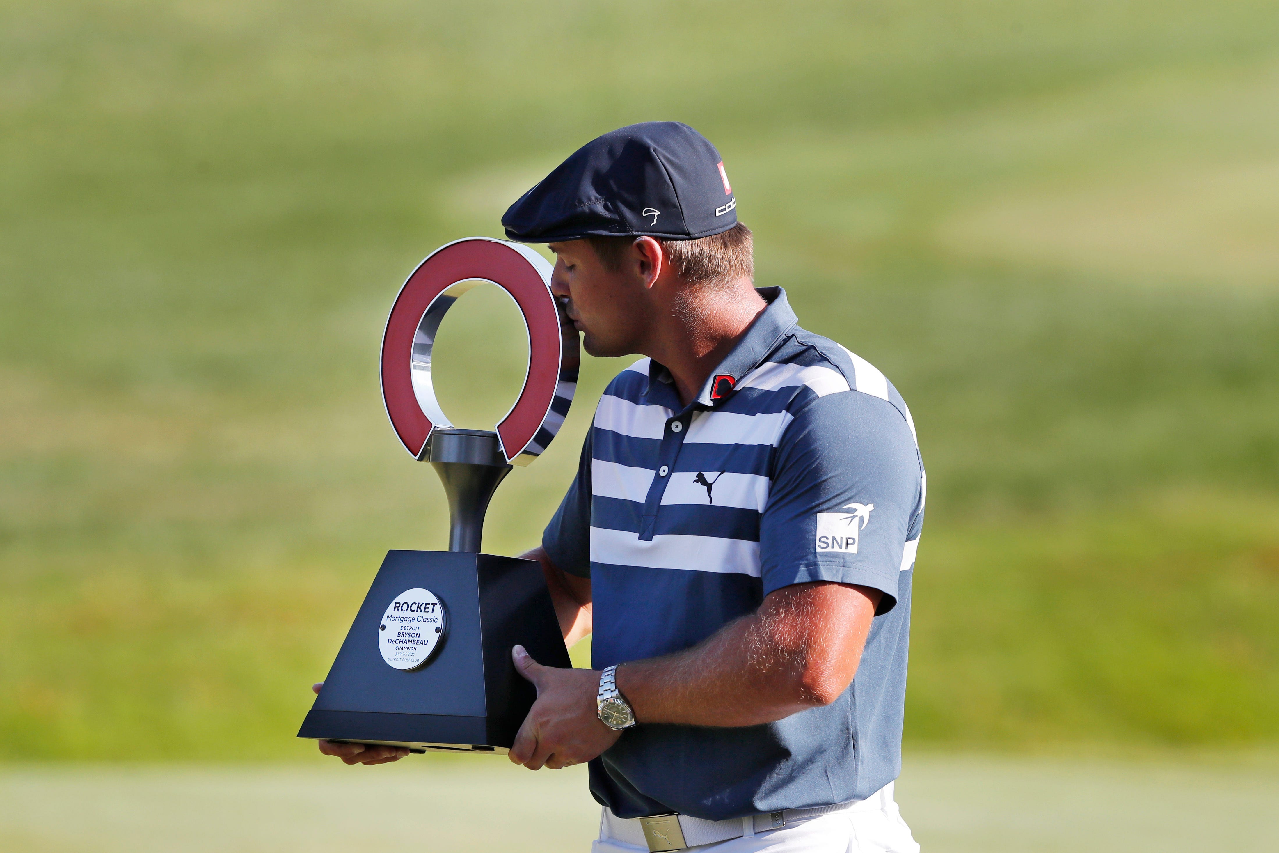 Bryson DeChambeau kisses the Rocket Mortgage Classic golf tournament trophy after winning in 2020.