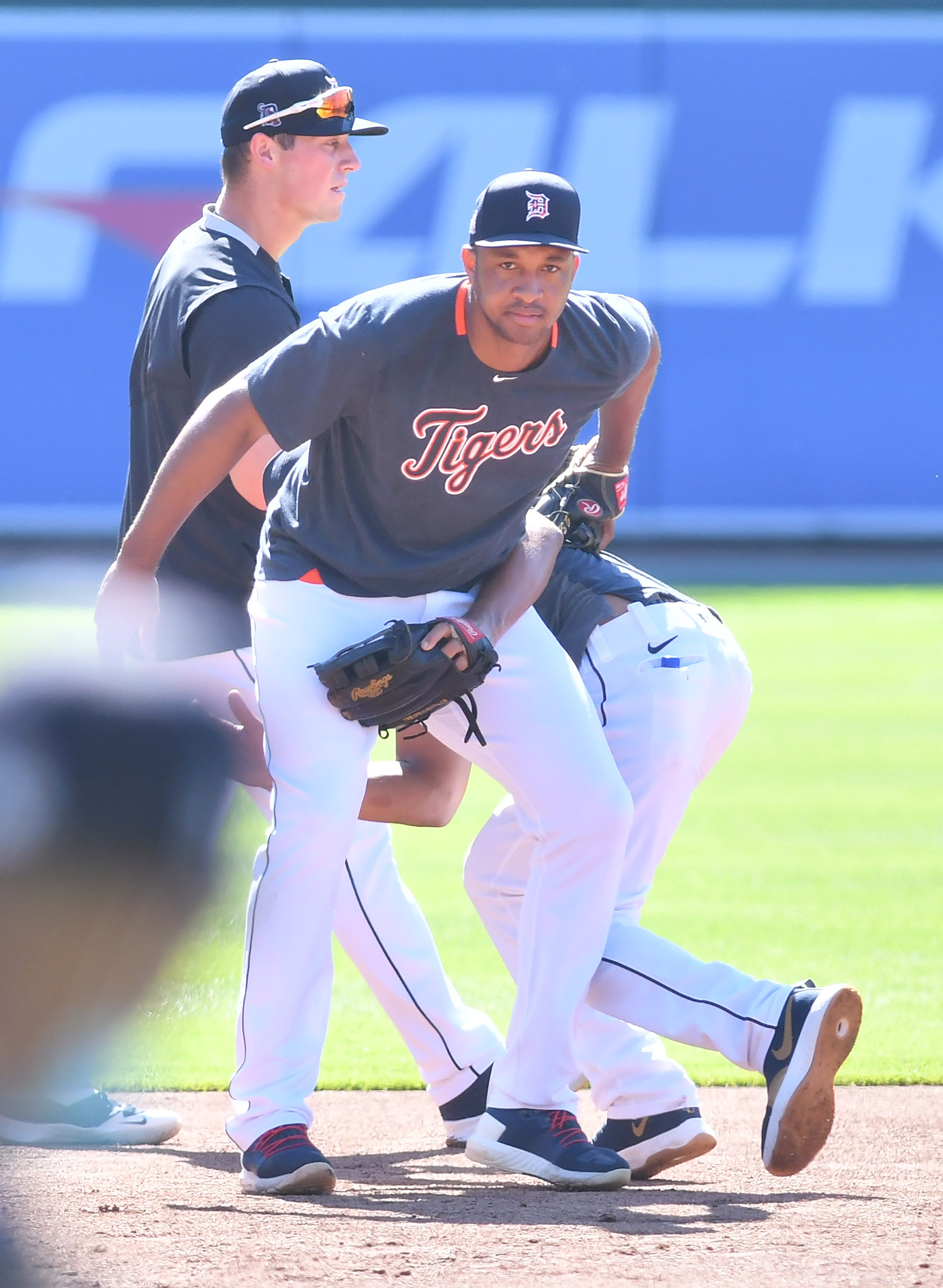 Tigers ' Jeimer Candelario jumps behind Jonathan Schoop after a ground ball came their way during simultaneous batting practice and infield practice.