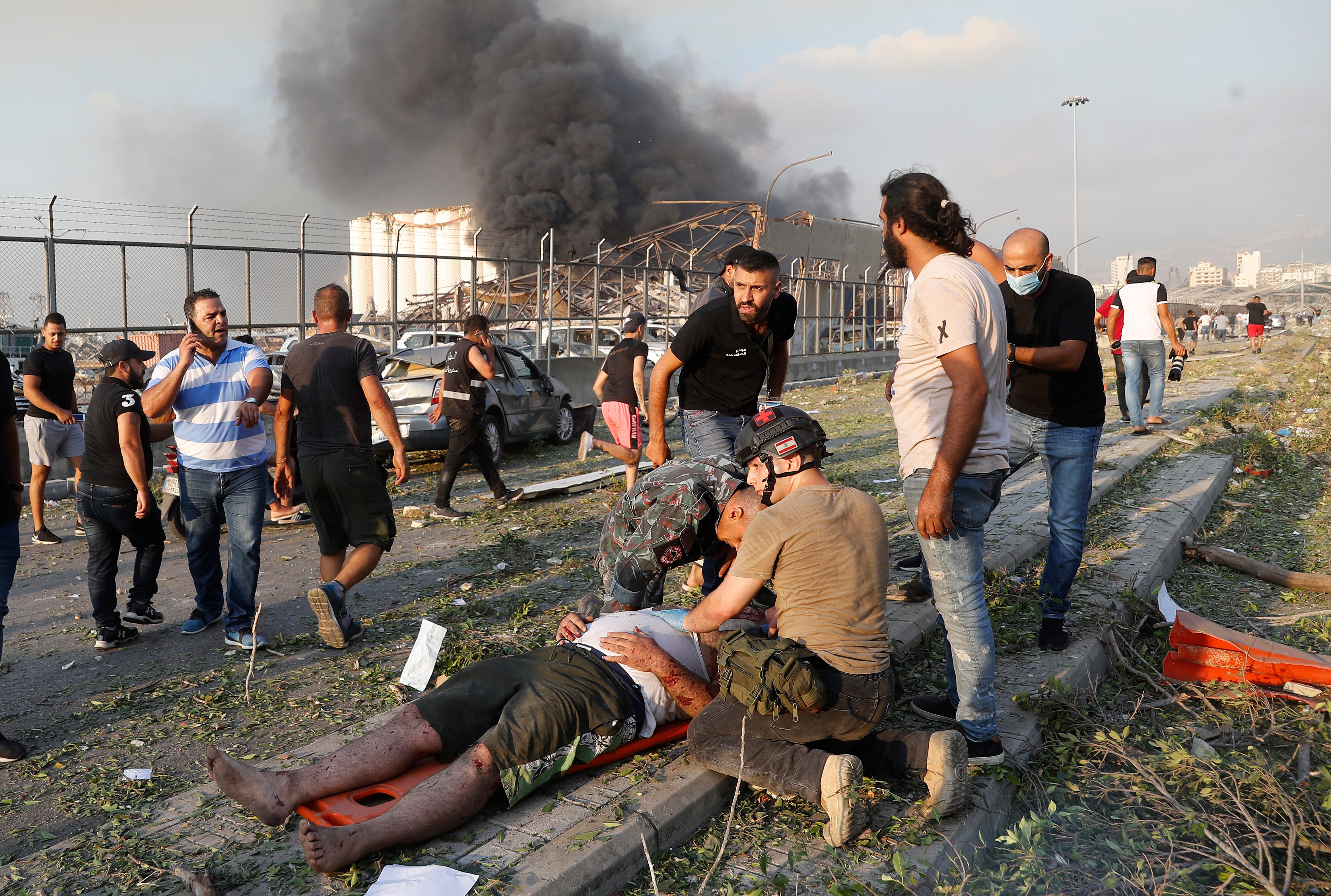 Rescue workers help an injured man at the explosion scene. Massive explosions rocked downtown Beirut, Lebanon on Tuesday, flattening much of the port, damaging buildings and blowing out windows and doors as a giant mushroom cloud rose above the capital.