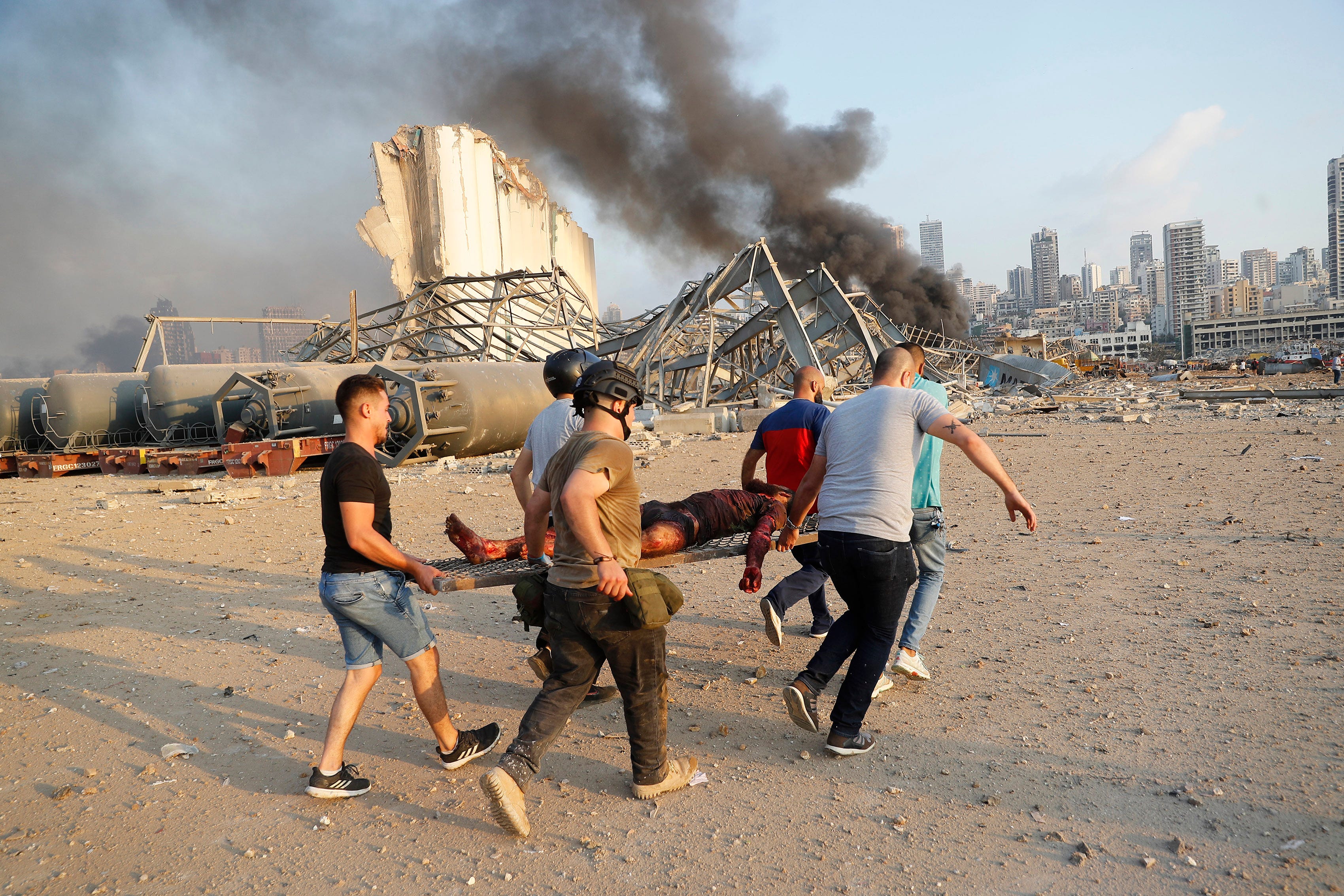 Civilians carry a victim at the explosion scene that hit the seaport, in Beirut Lebanon.