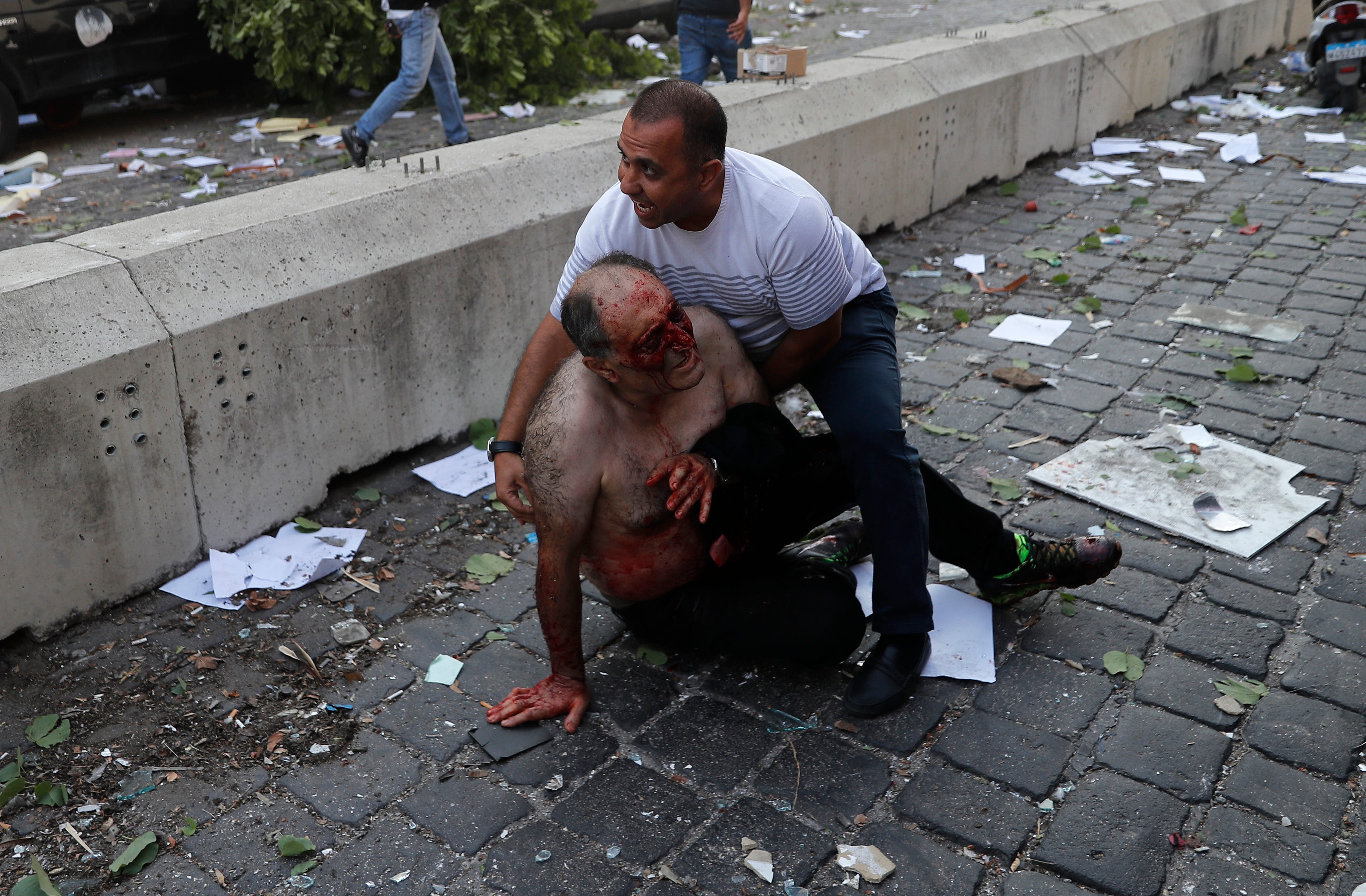 Lebanese man helps an injured man who was wounded.