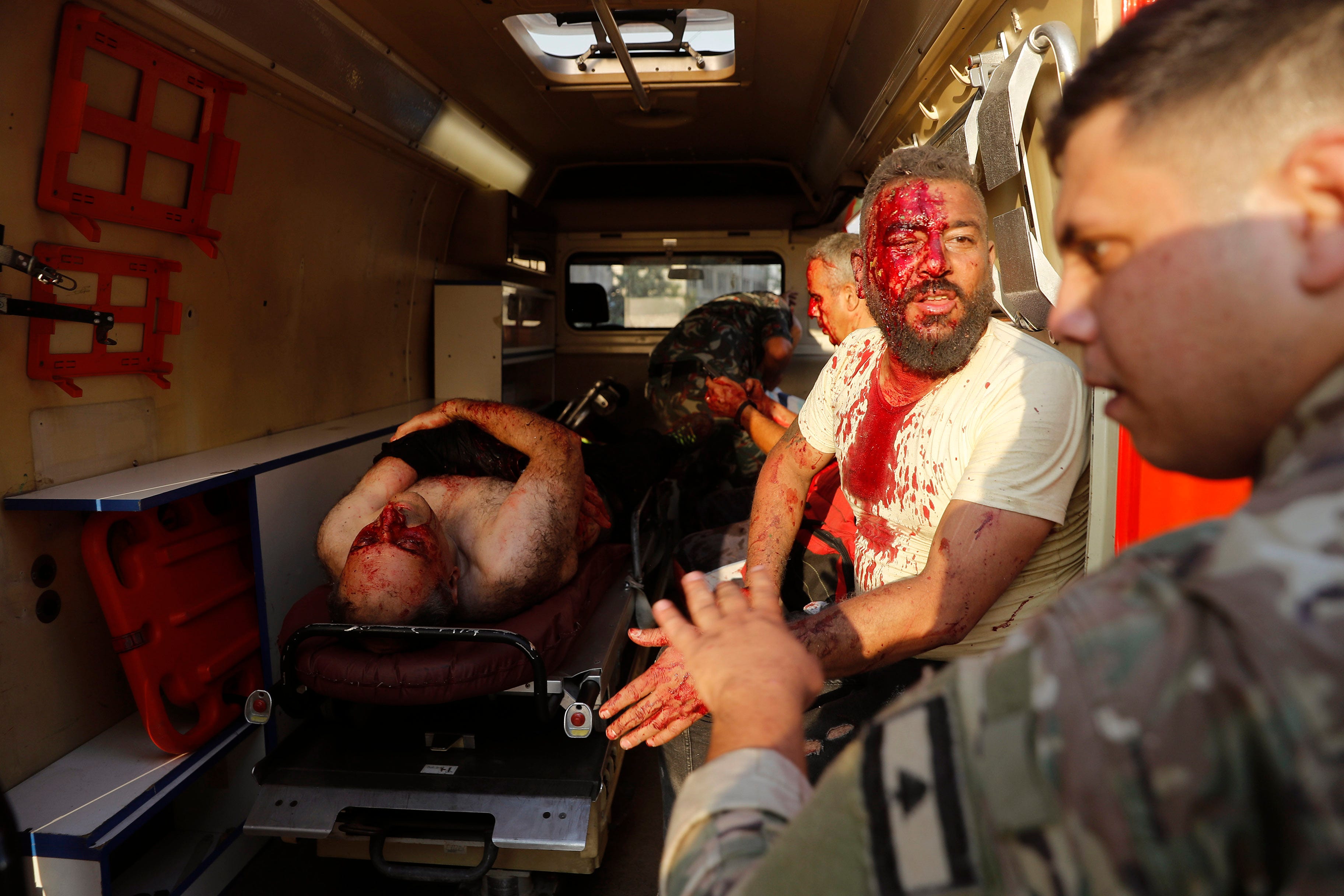 A Lebanese soldier, right, checks injured men who sit inside an ambulance at the explosion scene.