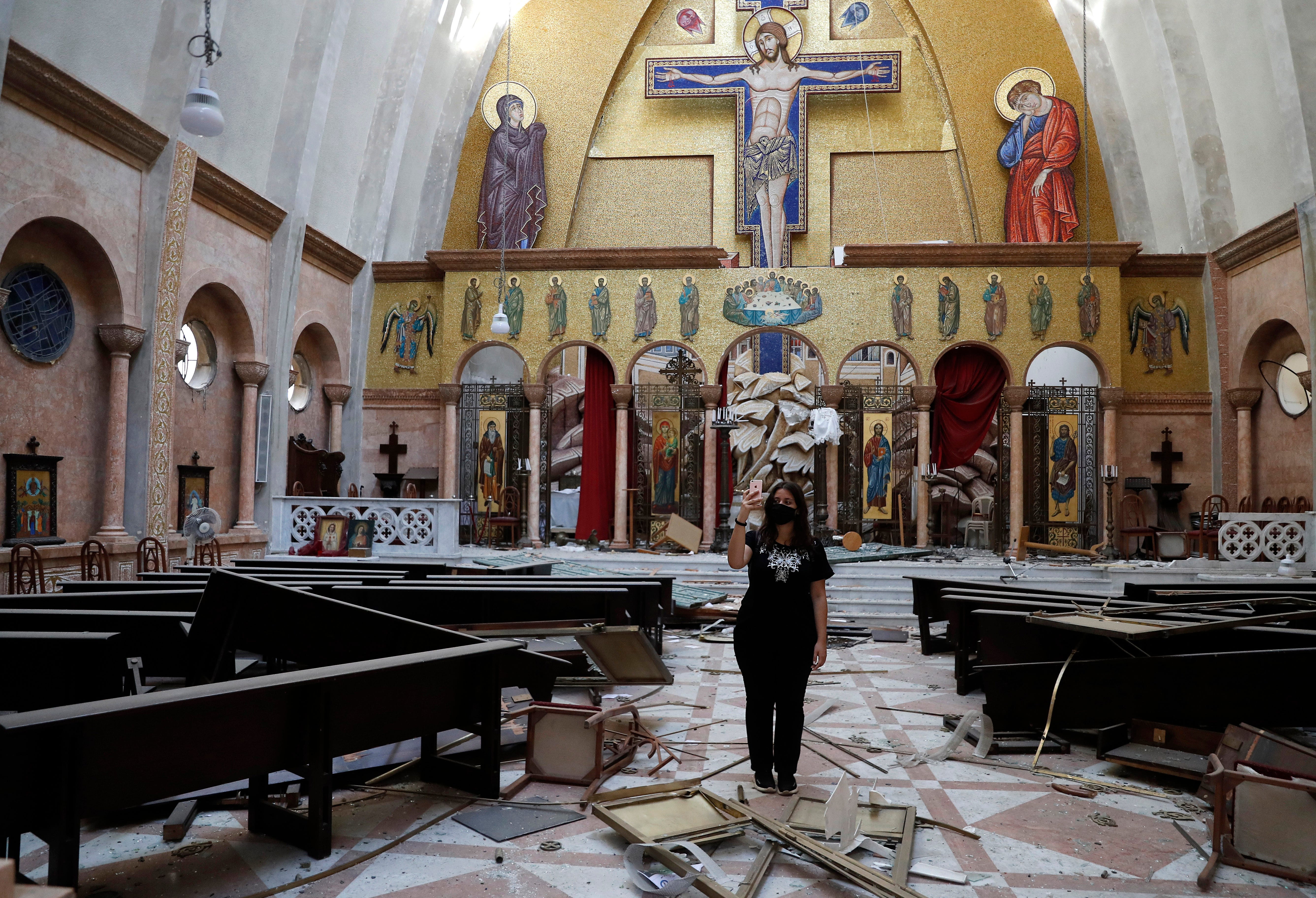 A woman takes pictures of a damaged church, after an explosion hit the seaport of Beirut, Lebanon, Wednesday, Aug. 5, 2020. Residents of Beirut awoke to a scene of utter devastation on Wednesday, a day after a massive explosion at the port sent shock waves across the Lebanese capital.