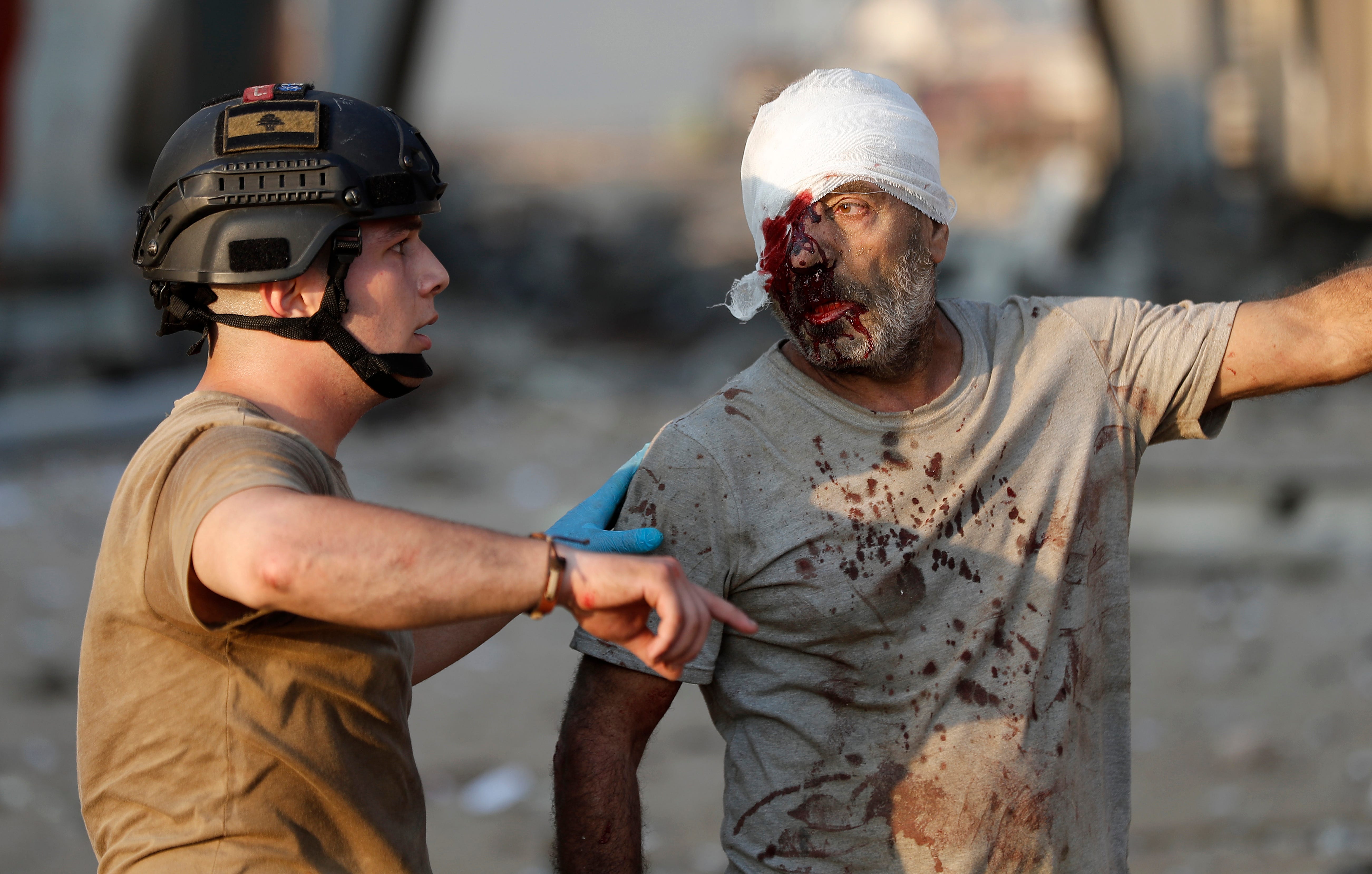 A Lebanese soldier directs an injured sailor to evacuate the explosion scene.