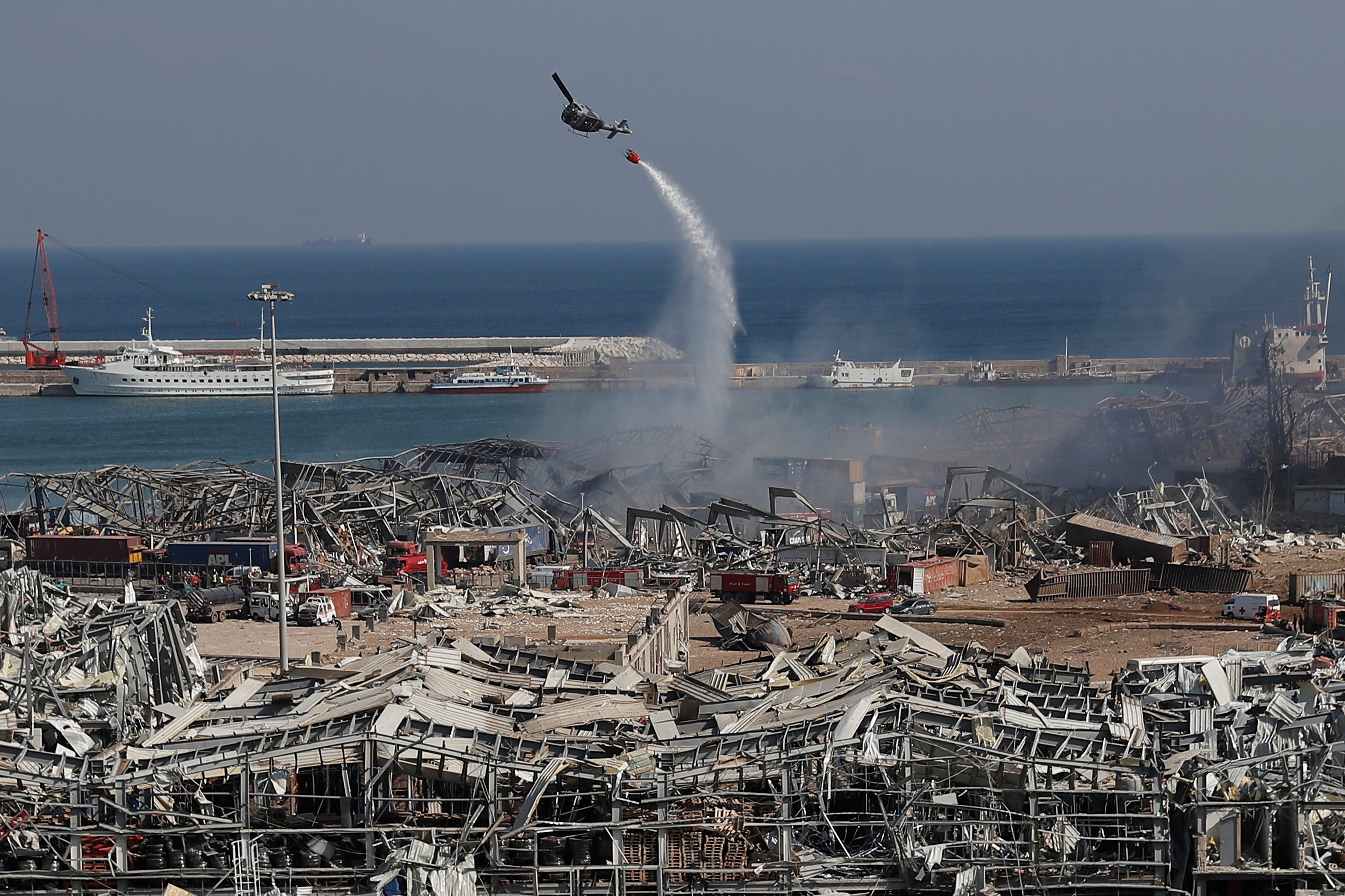 An army helicopter drops water at the scene of Tuesday's massive explosion that hit the seaport of Beirut, Lebanon, Wednesday, Aug. 5, 2020. Residents of Beirut awoke to a scene of utter devastation on Wednesday, a day after a massive explosion at the port sent shock waves across the Lebanese capital, killing dozens of people and wounding thousands.