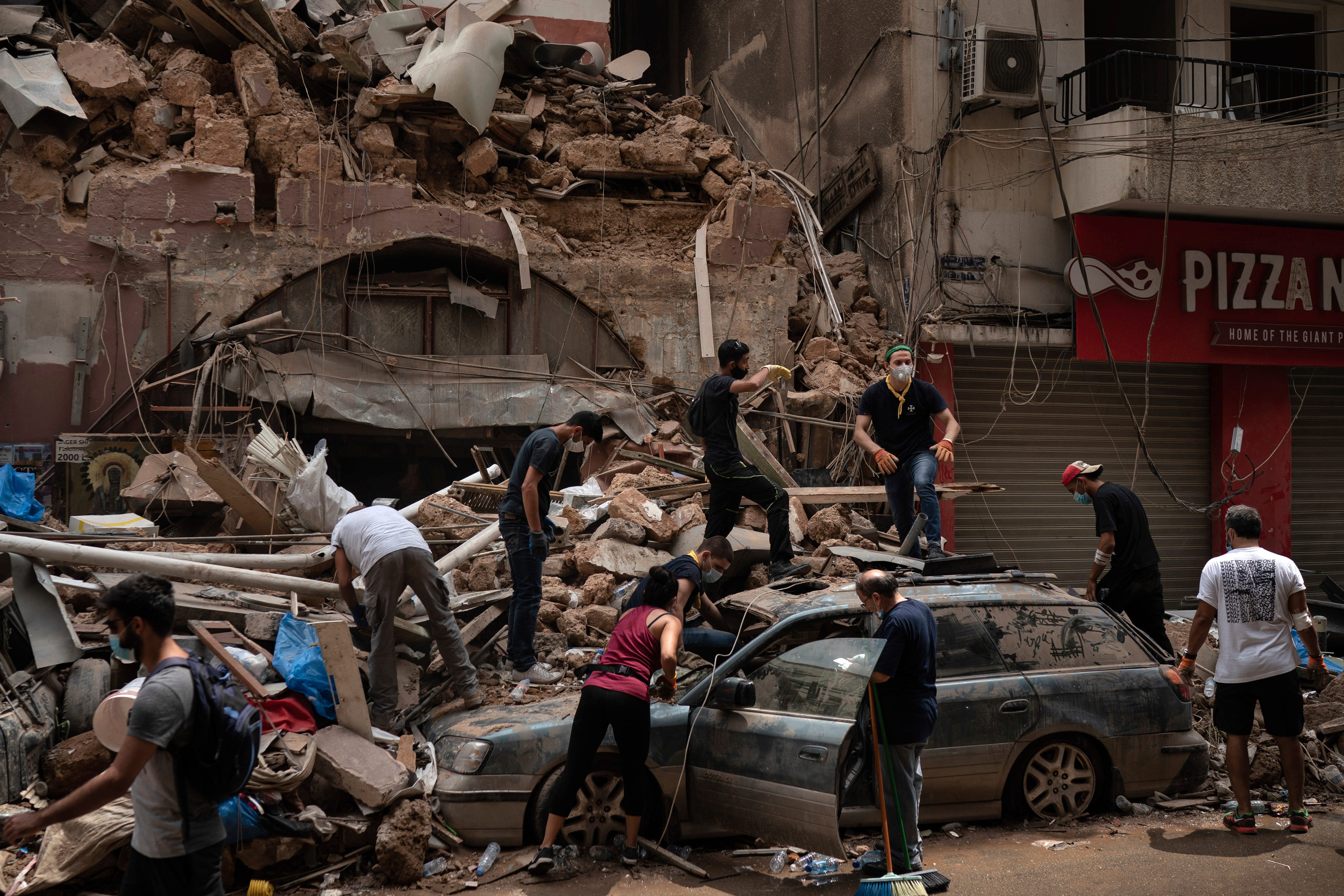 People remove debris from a house damaged by Tuesday's explosion in the seaport of Beirut, Lebanon, Friday, Aug. 7, 2020.  Rescue teams were still searching the rubble of Beirut's port for bodies on Friday, nearly three days after the massive explosion sent a wave of destruction through Lebanon's capital.