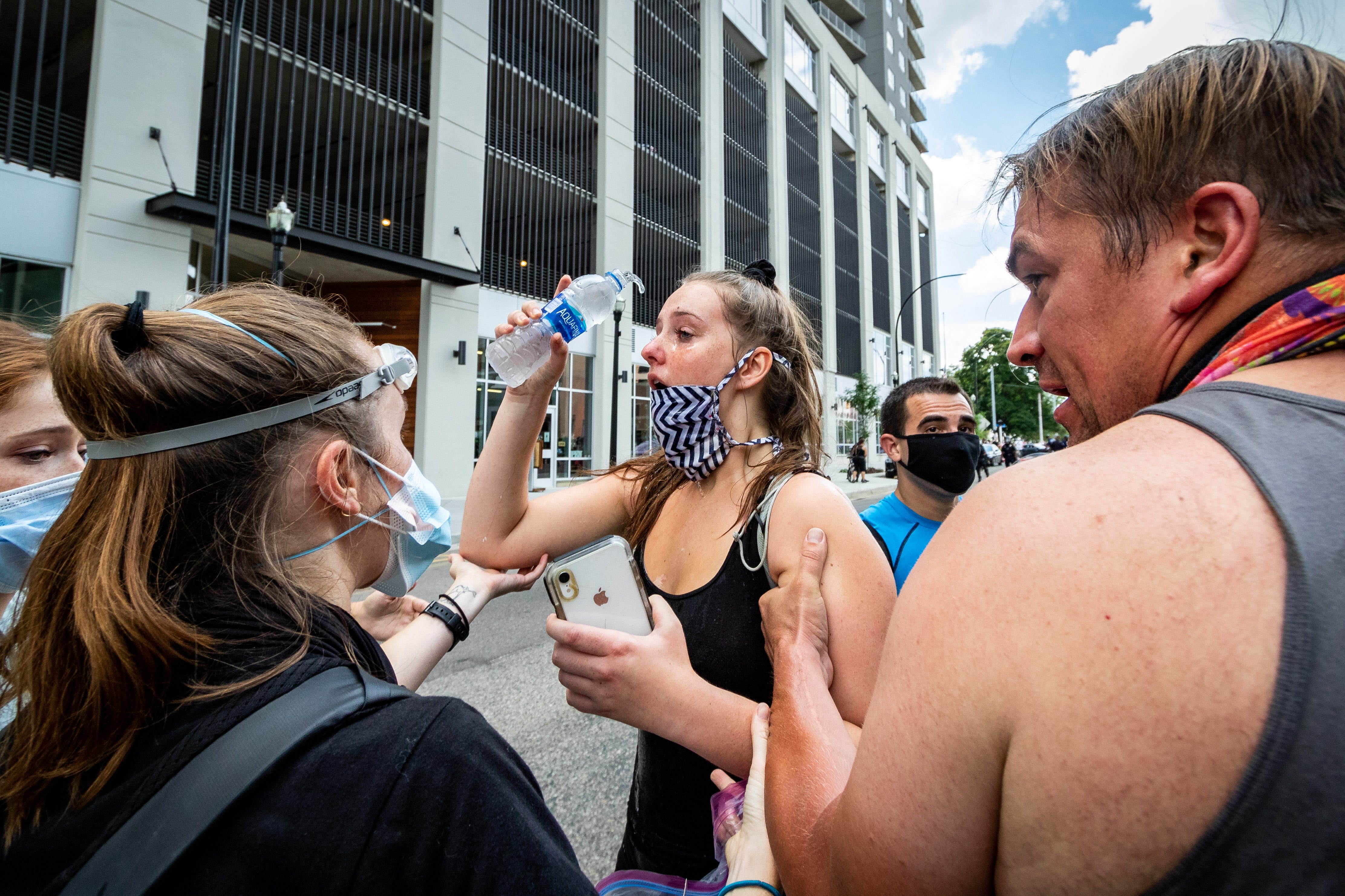 A counter-protestor washes a chemical irritant from her eyes with the help of others. Members of Proud Boys, antifa, and a local church clash with each other and local and Michigan State Police at Arcadia Creek Festival Plaza in Kalamazoo on August 15, 2020.