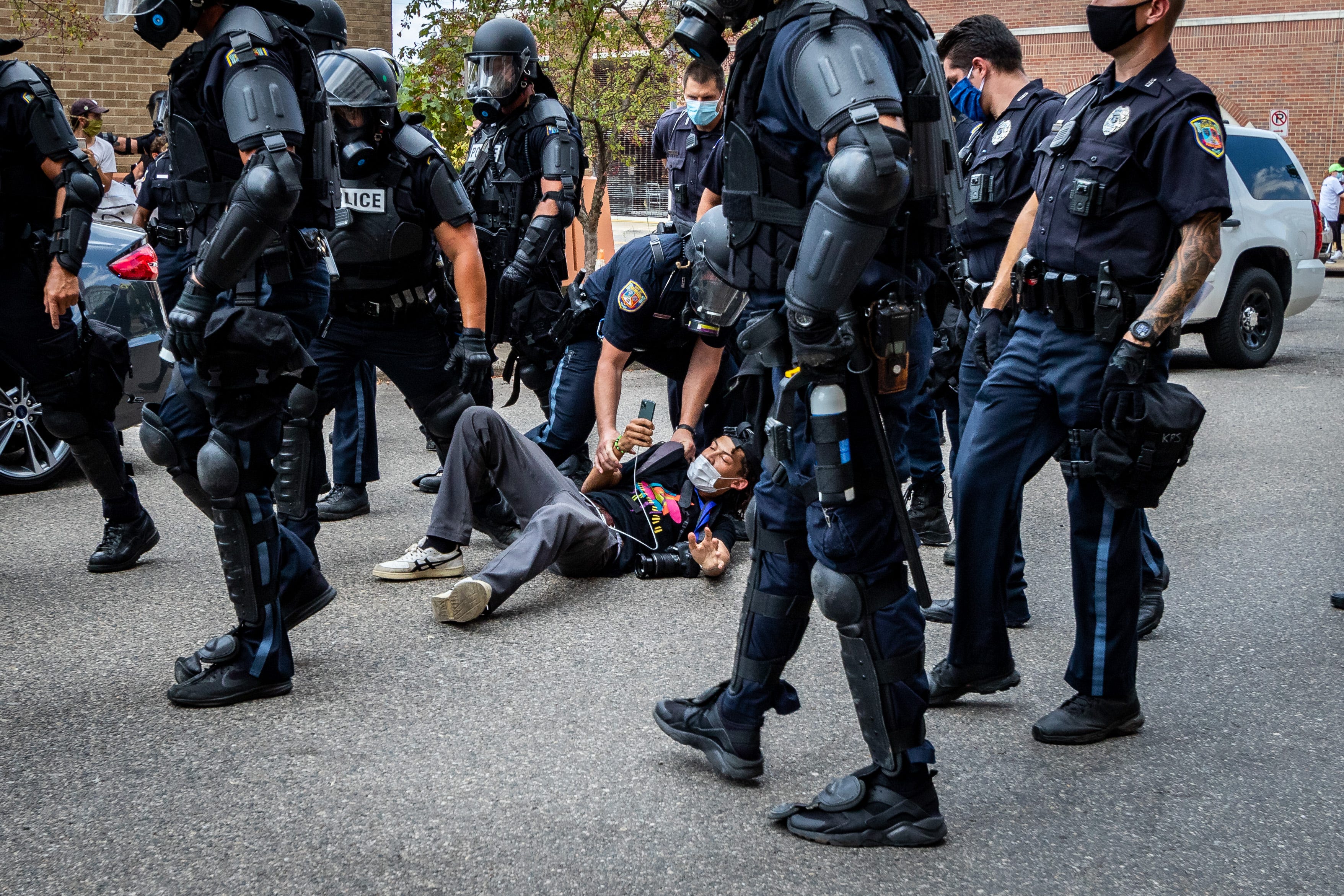 Kalamazoo Police in riot gear arrest an MLive reporter.
