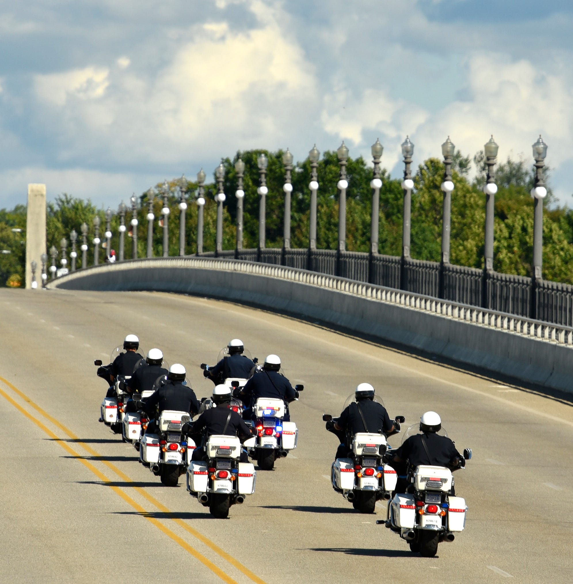 Officers from the DPD Motor Unit cross the Douglas McArthur Bridge as they leave Belle Isle to escort another group of family members of COVID-19 victims onto the island.