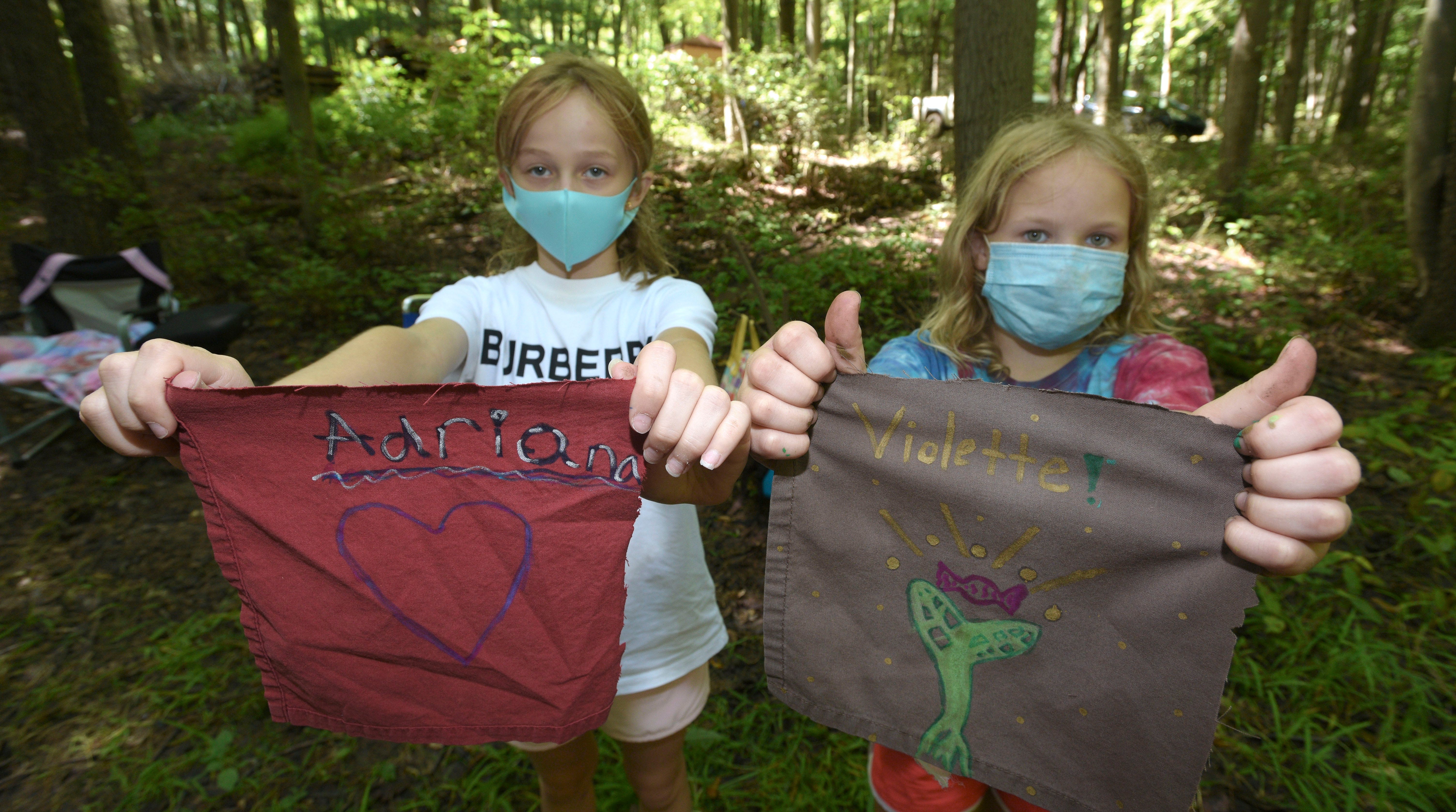 Adriana Oleksy, left, and Violette Harvat, both 10 and of Rochester, show off the flags they made with their names and something that represents them in The Holler, an outdoor classroom. Adriana's flag has a heart showing how much she loves to draw hearts and Violette's flag shows a green tree sapling and red piece of candy showing how much she loves to climb trees and eat candy.