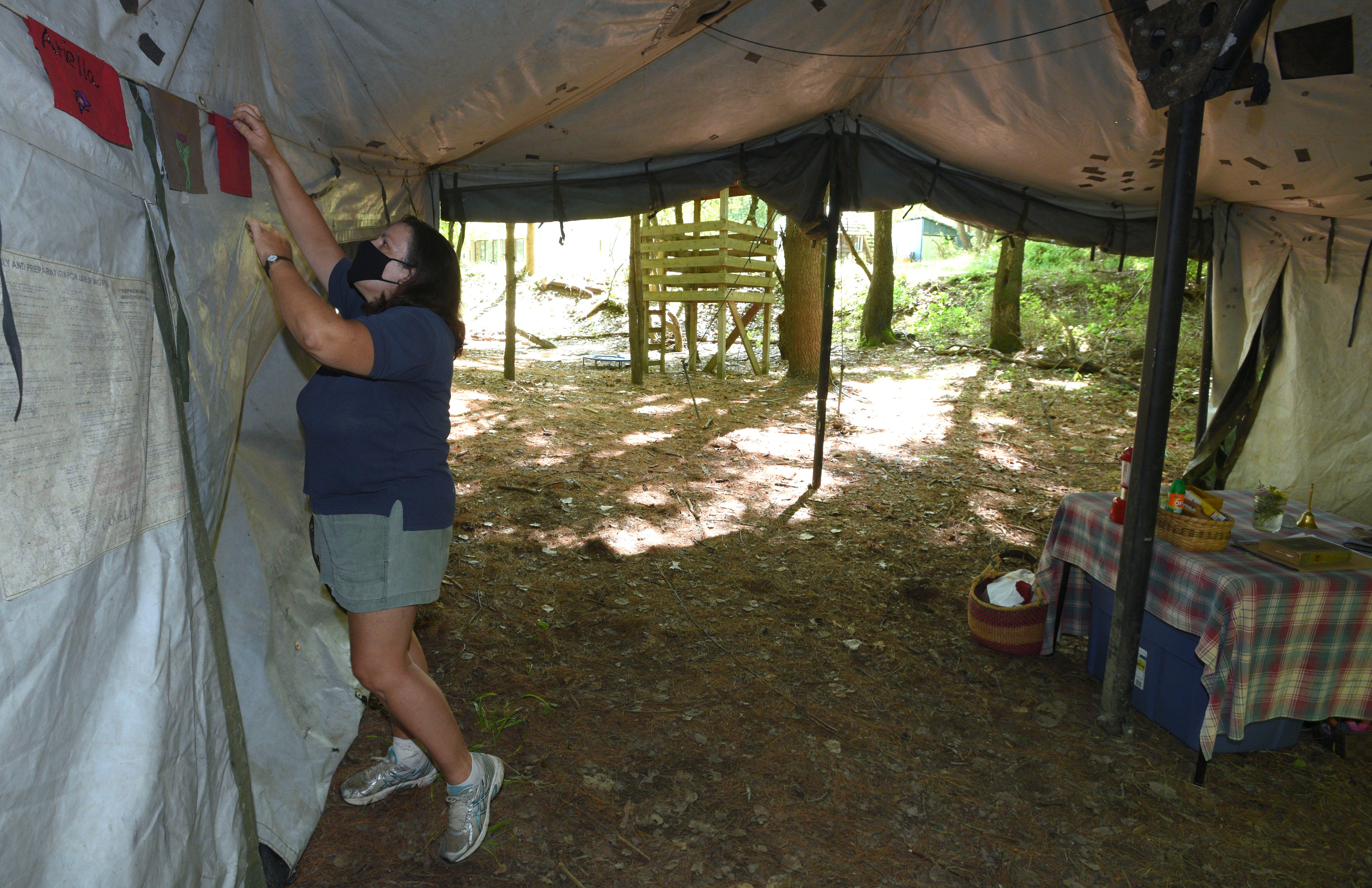 Deborah Byrd, of Addison Twp,, teacher of the 9-11 year olders, displays her students hand-made flags on the wall of her Army tent in The Hollar, her outdoor classroom.