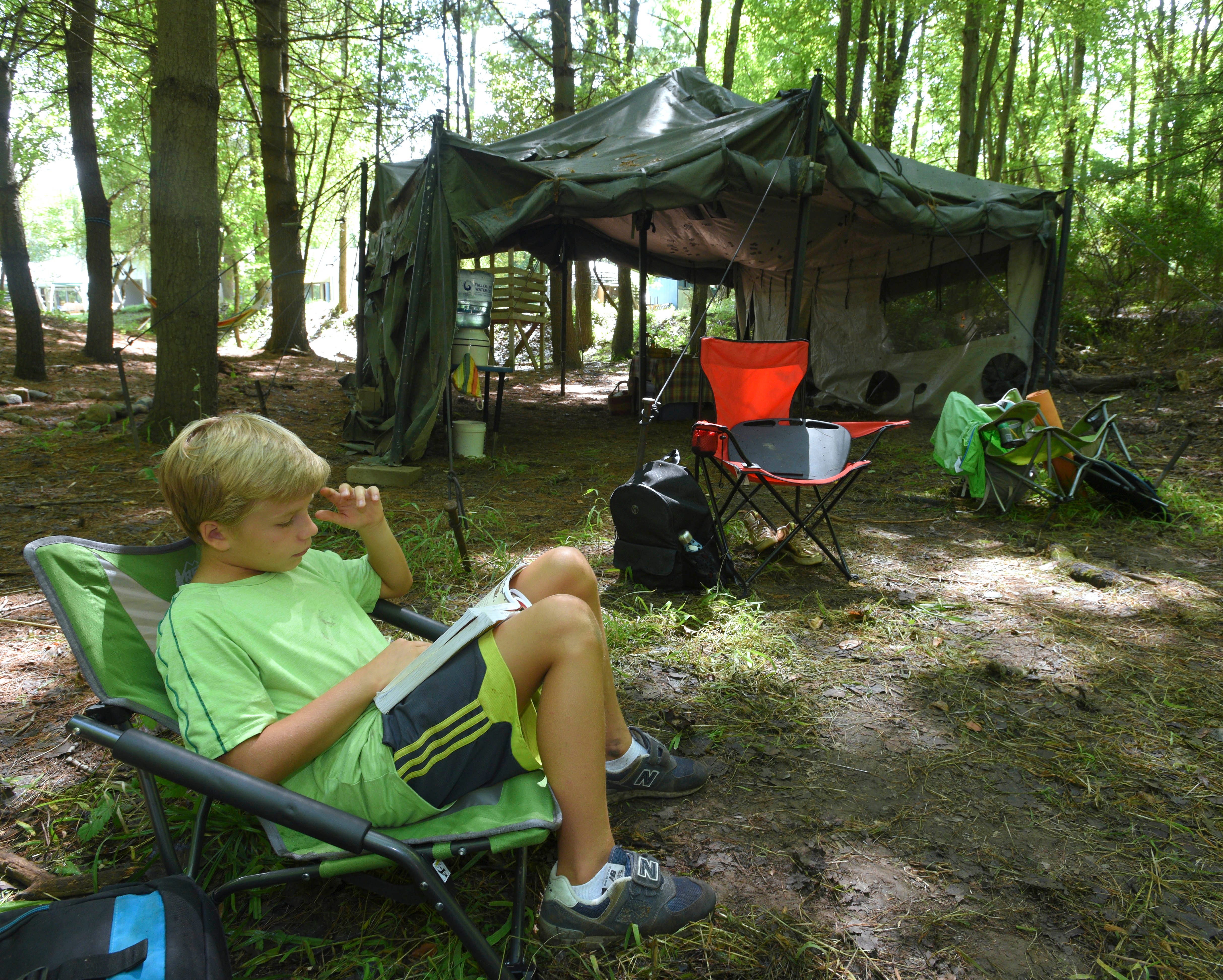 Alik Sifford, 11, of Shelby Twp., reads a book in front of an Army tent in The Holler, an outdoor classroom.