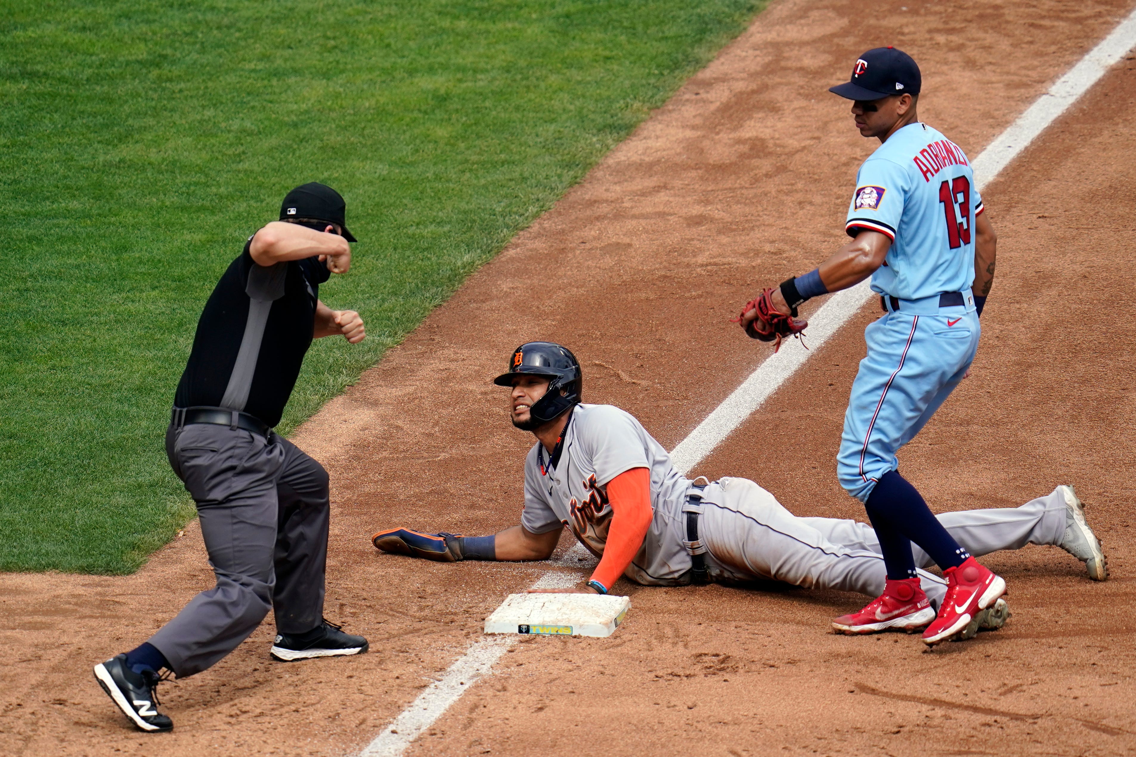 Third base umpire Chris Segal signals an out after Minnesota Twins third baseman Ehire Adrianza, right, tagged Detroit Tigers' Victor Reyes who was attempting to reach third after a Twins throwing error on a pickoff-attempt at first base in the fifth inning.