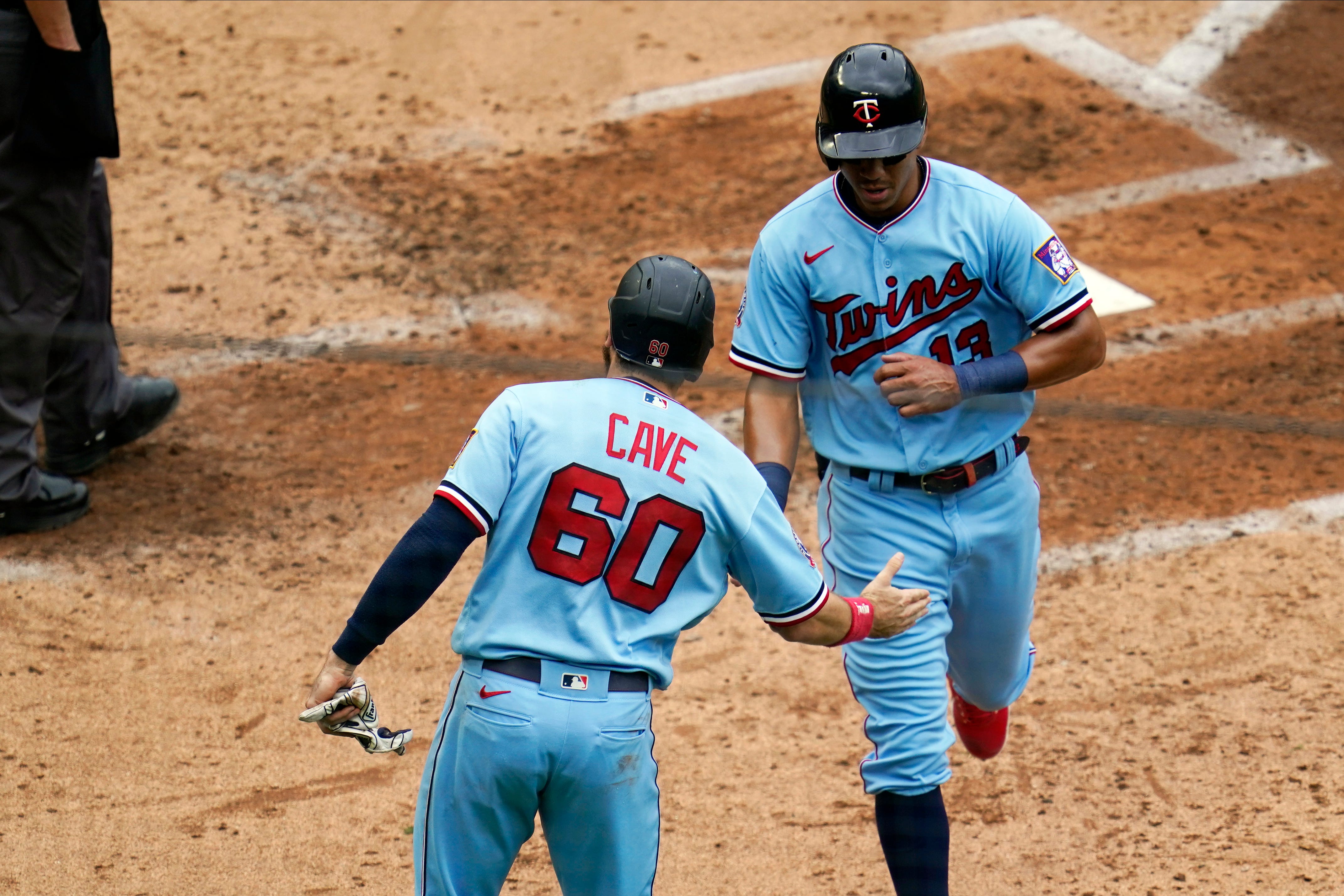 Minnesota Twins ' Jake Cave (60) and Ehire Adrianza celebrate as they score on a two-run single by Willians Astudillo off Detroit Tigers pitcher Casey Mize in the third inning.