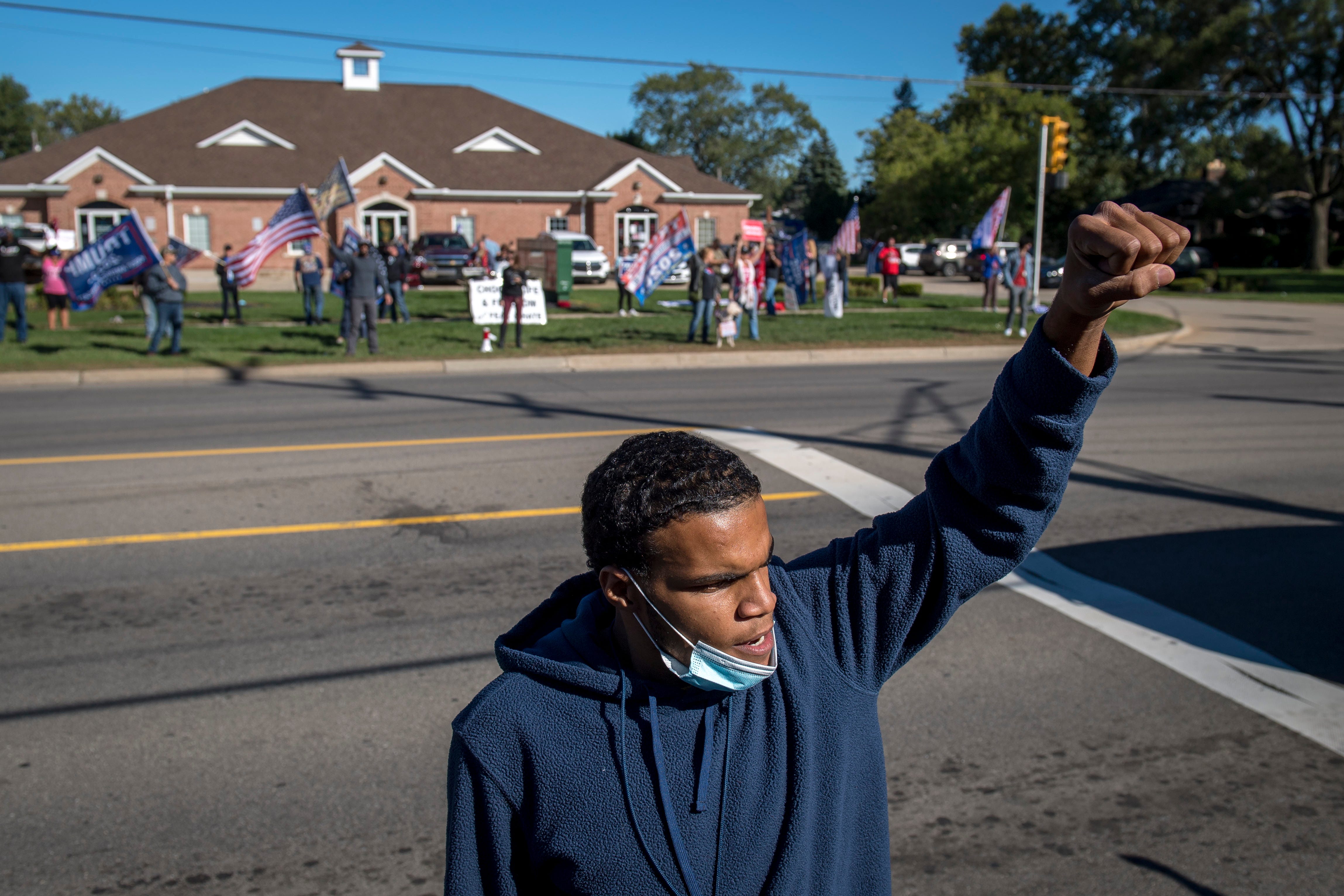 Jordan Williams raises his fist while Trump supporters counter protest before the March Against Racism in Warren on Sept. 19, 2020. The march in Warren occurred in response to the city called hate crimes against residents Candace Hall, her husband Eddie and their two children.