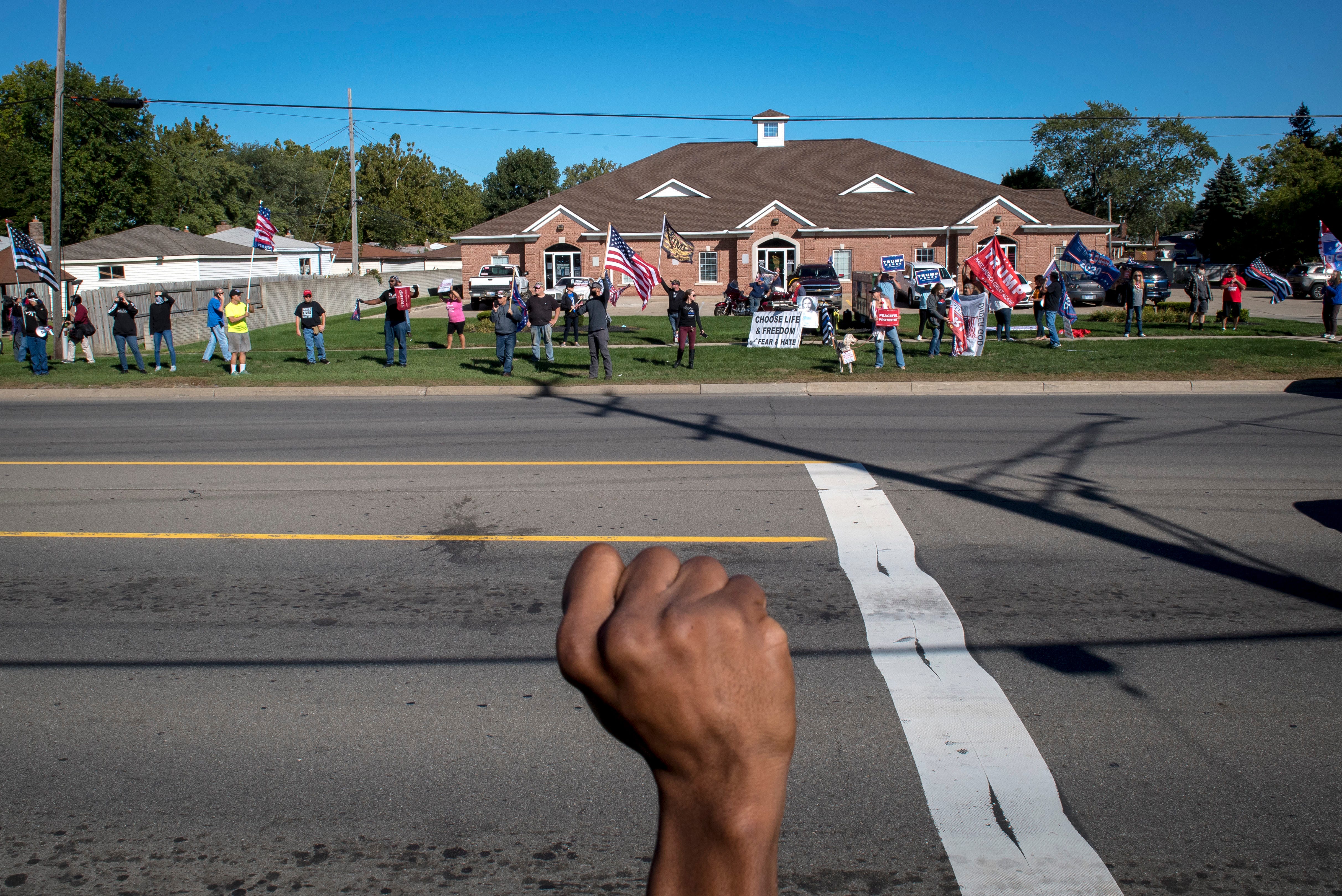 A Detroit Will Breathe protester raises their fist while Trump supporters counter protest before the March Against Racism in Warren on Sept. 19, 2020. The march in Warren occurred in response to the city called hate crimes against residents Candace Hall, her husband Eddie and their two children.
