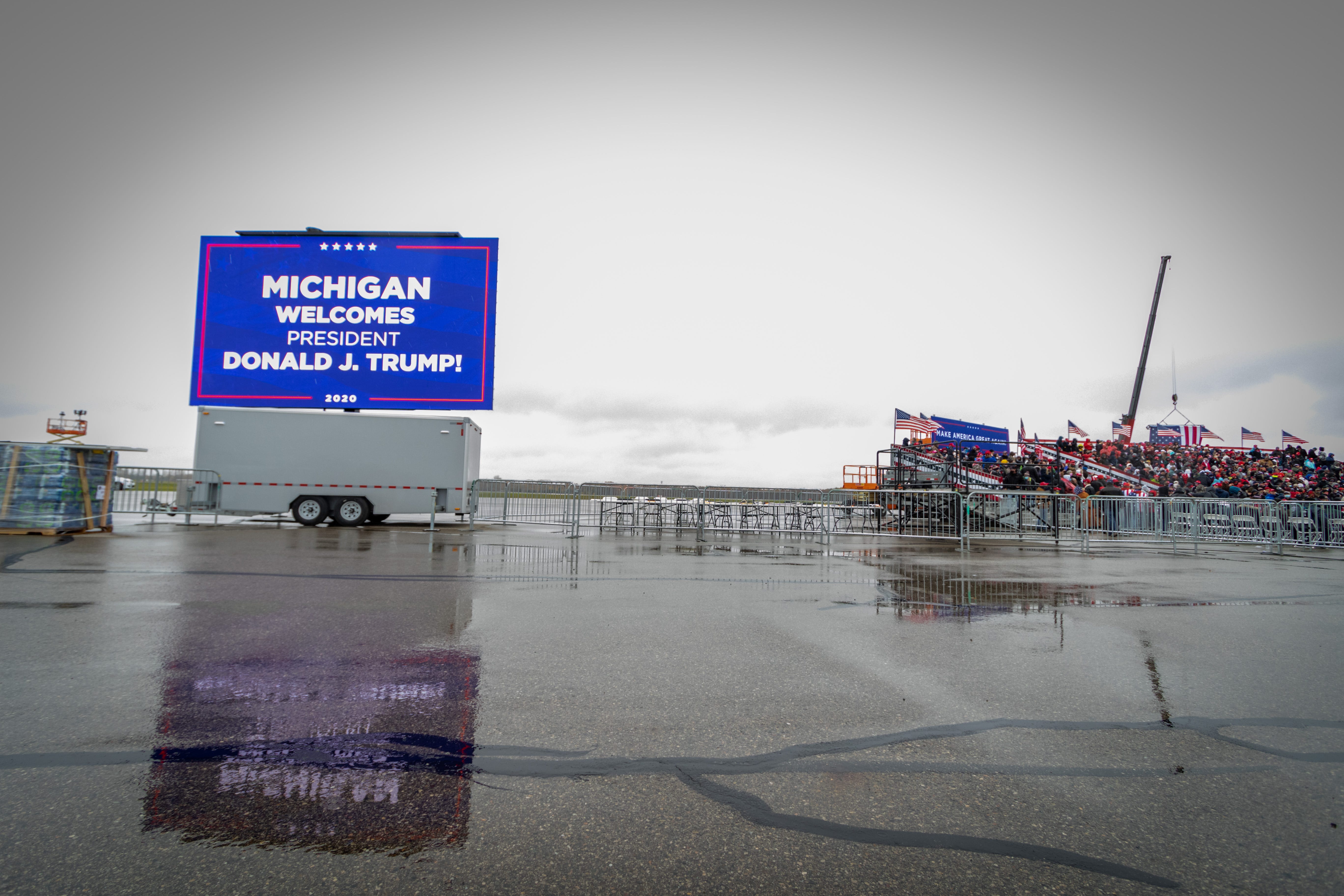 A video billboard welcoming President Trump reflects on the rain-soaked tarmac before President Donald Trump's campaign rally in Lansing, Michigan on October 27, 2020, one week before the general election.