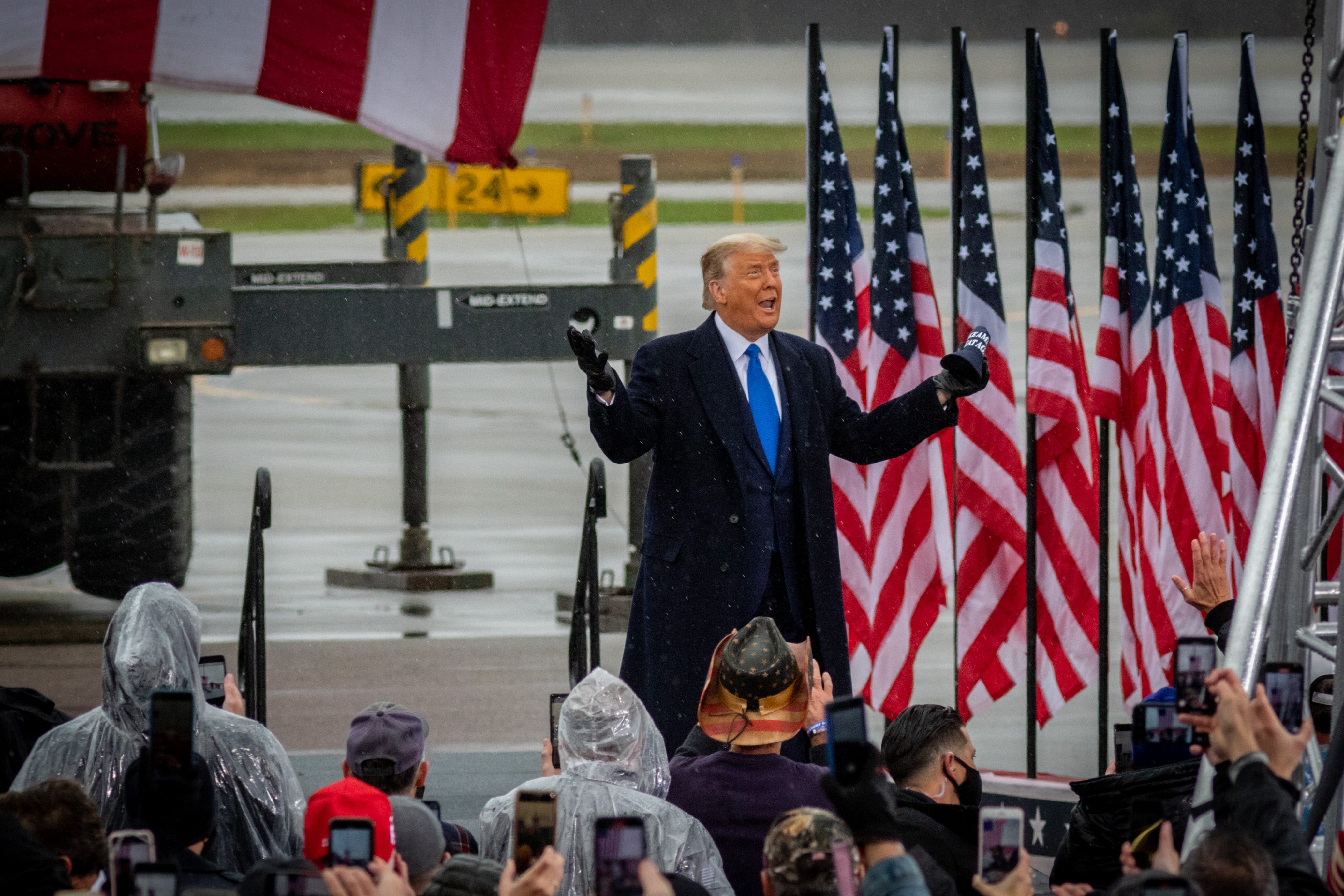 President Donald Trump reacts to the rain as he arrives at his campaign rally in Lansing.