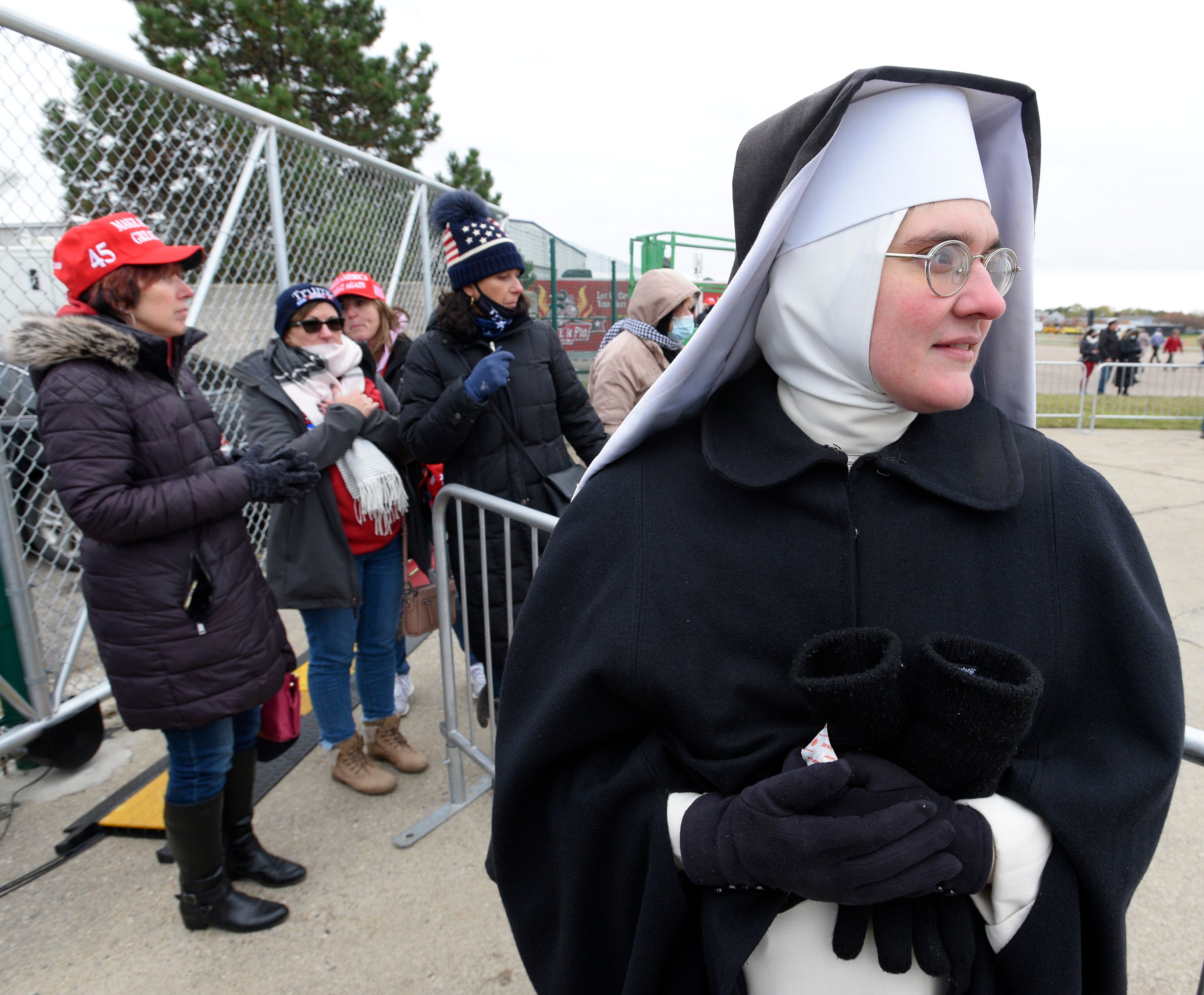 A Dominican nun waits for a friend as supporters of President Donald Trump wait for his arrival at the Oakland International Airport in Waterford Township.