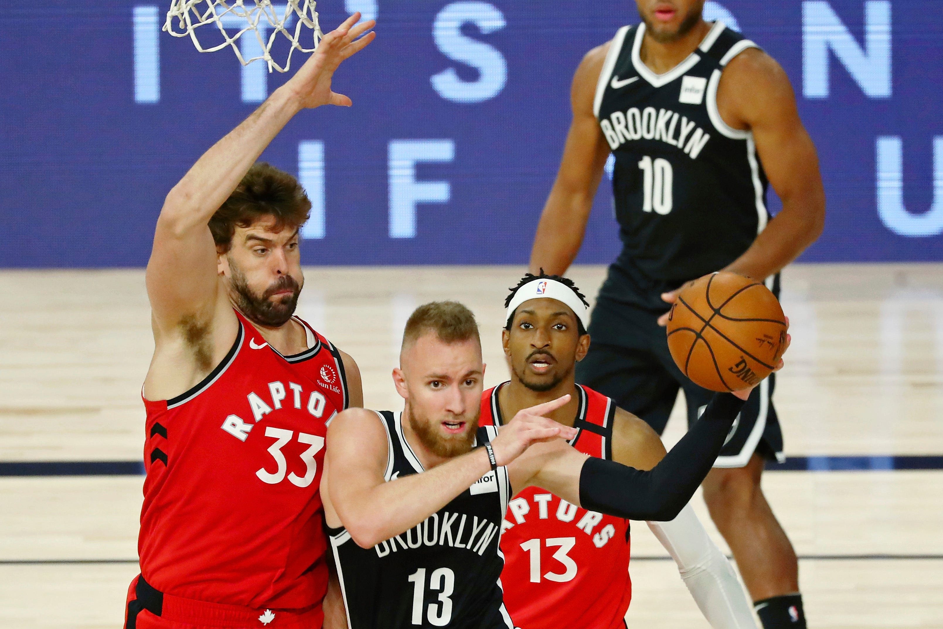 Brooklyn Nets guard Dzanan Musa (13) passes the ball while defended by Toronto Raptors center Marc Gasol (33) during the second half in Game 3 of an NBA basketball first-round playoff series, Friday, Aug. 21, 2020, in Lake Buena Vista, Fla.