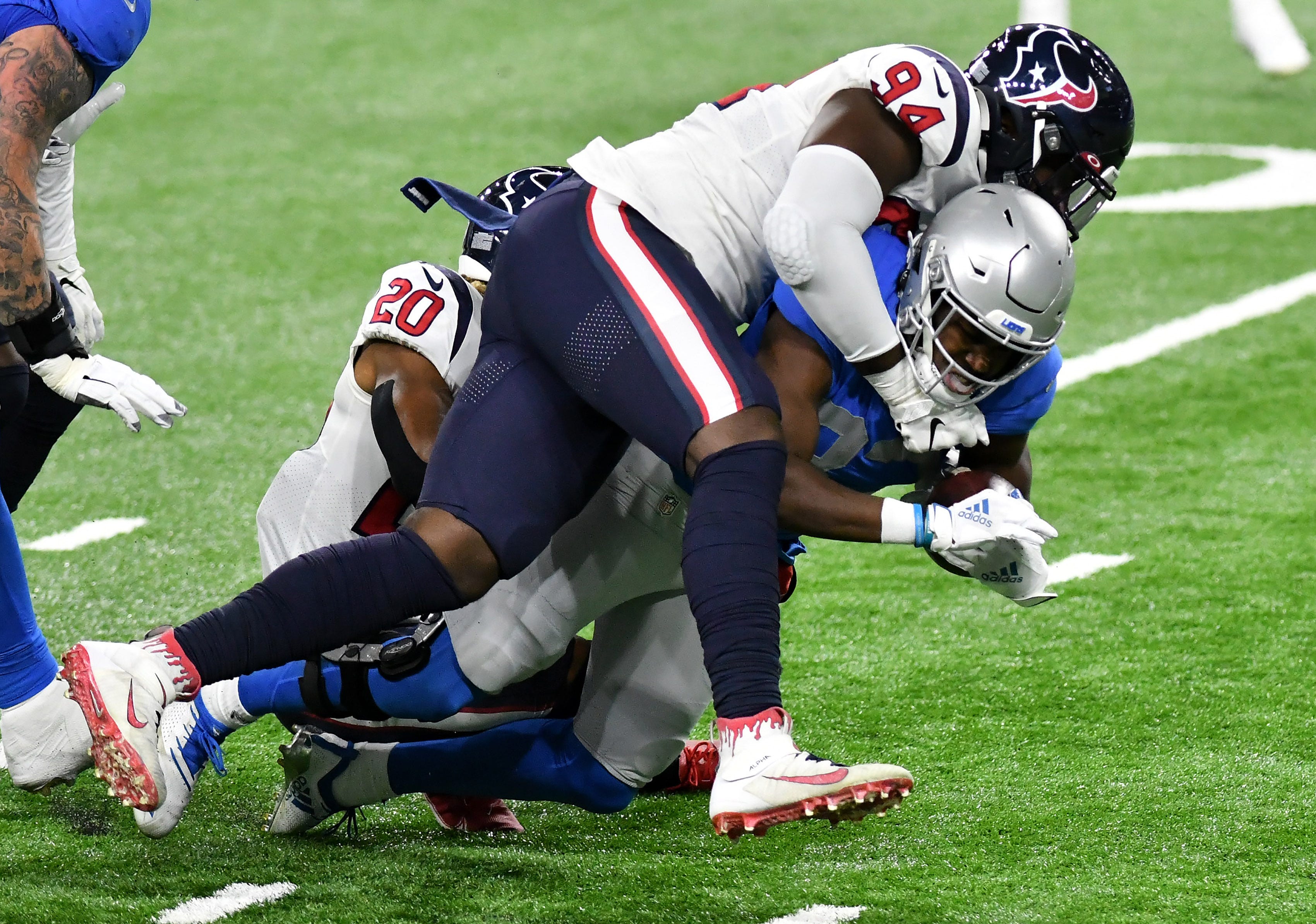 Texans defensive end Charles Omenihu (94) and Texans strong safety Justin Reid (20) bring down Lions running back Kerryon Johnson (33) in the first half.