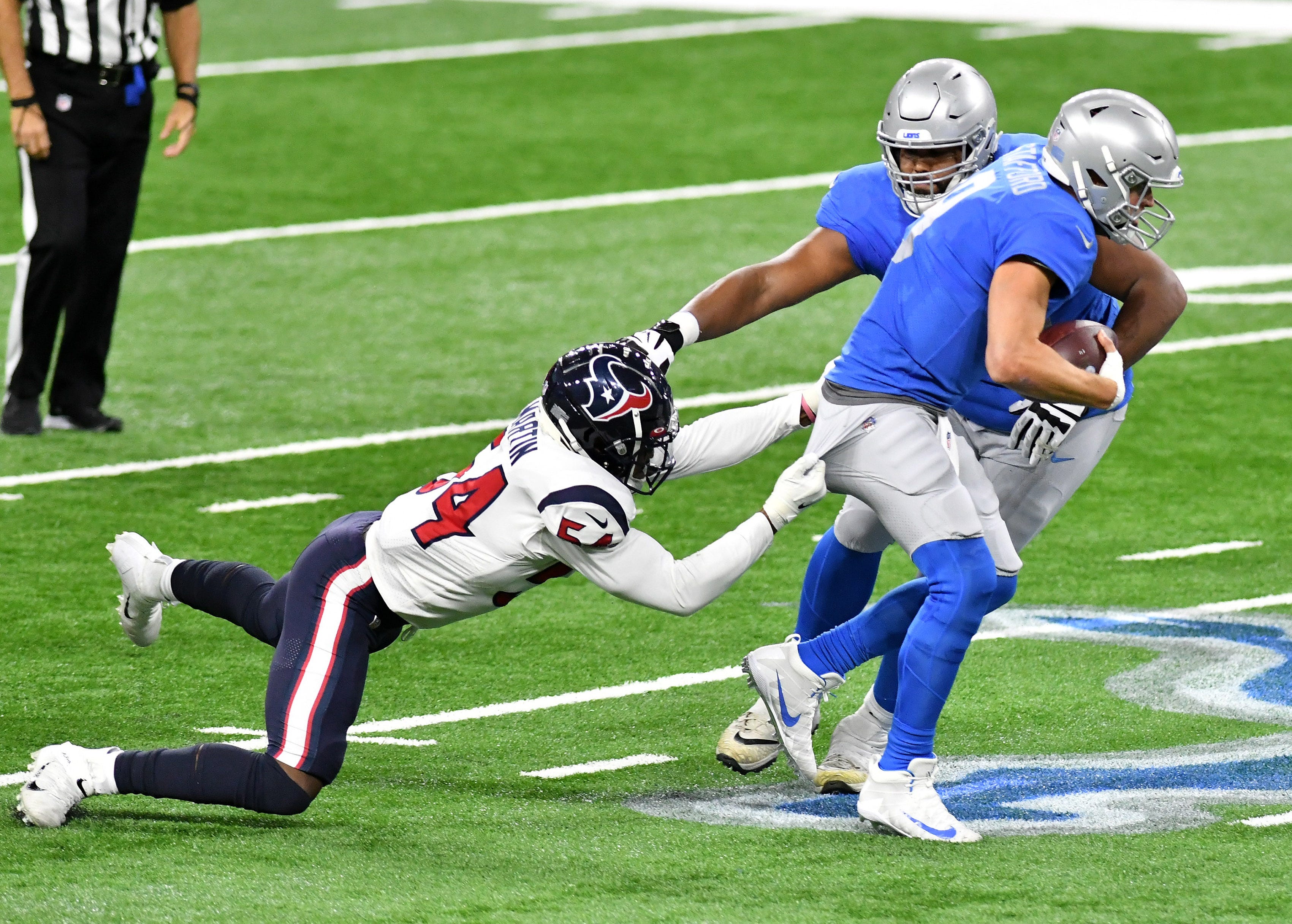 Texans linebacker Jake Martin (54) yanks on the pants of Lions quarterback Matthew Stafford (9) trying to tackle him in the first half.