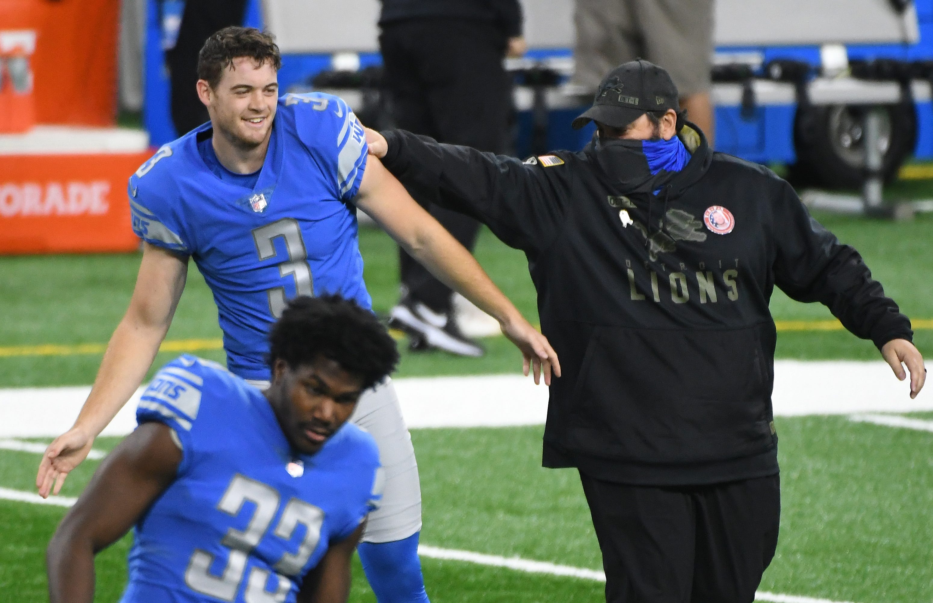 Lions head coach Matt Patricia, right, gives punter Jack Fox a playoff push as Detroit warms up on the field before the game against Washington on November 15, 2020.