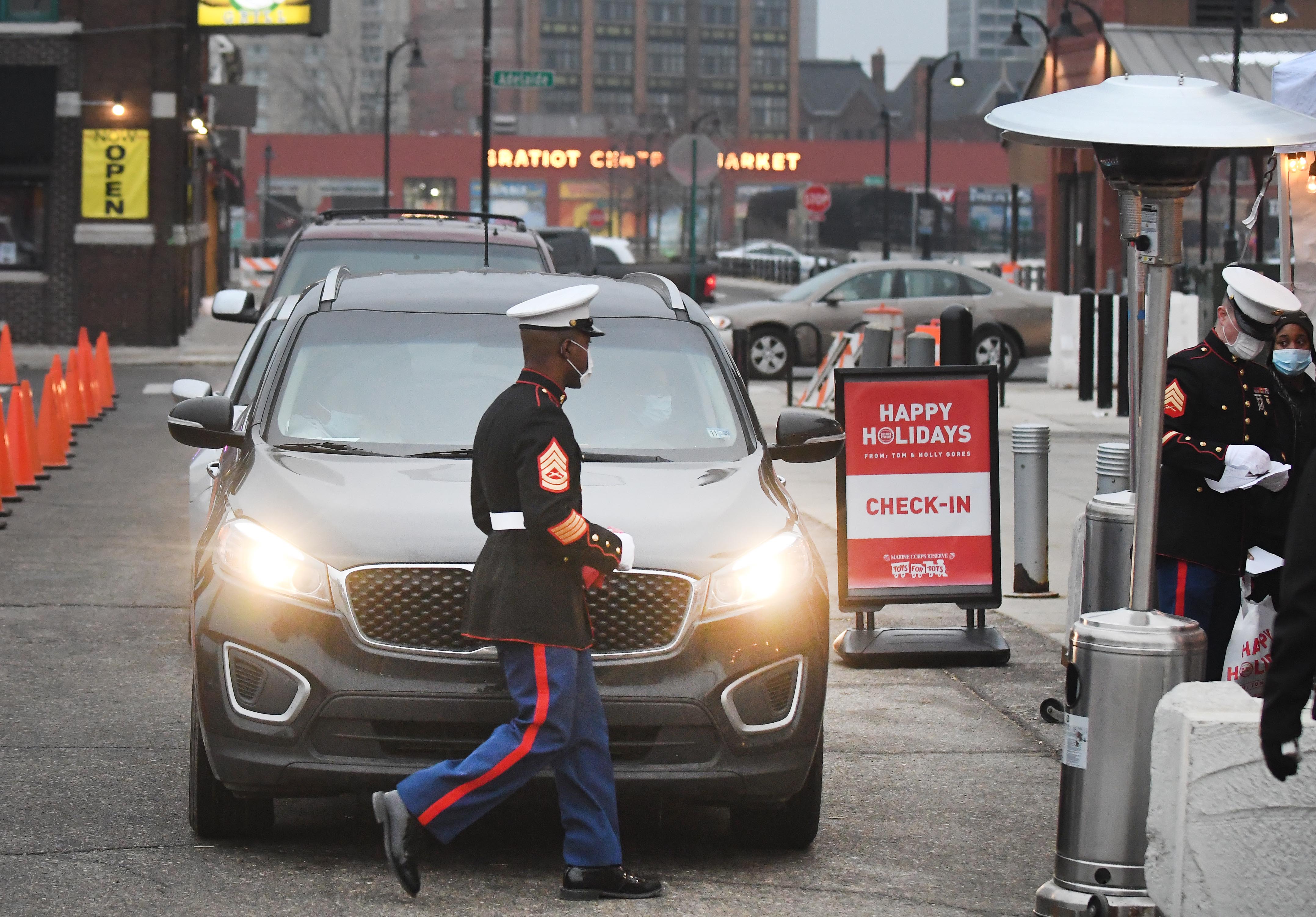 Marines and volunteers of the Marine Corps Reserve Toys for Tots program check in cars in line for a drive-through toy pickup in Eastern Market.
