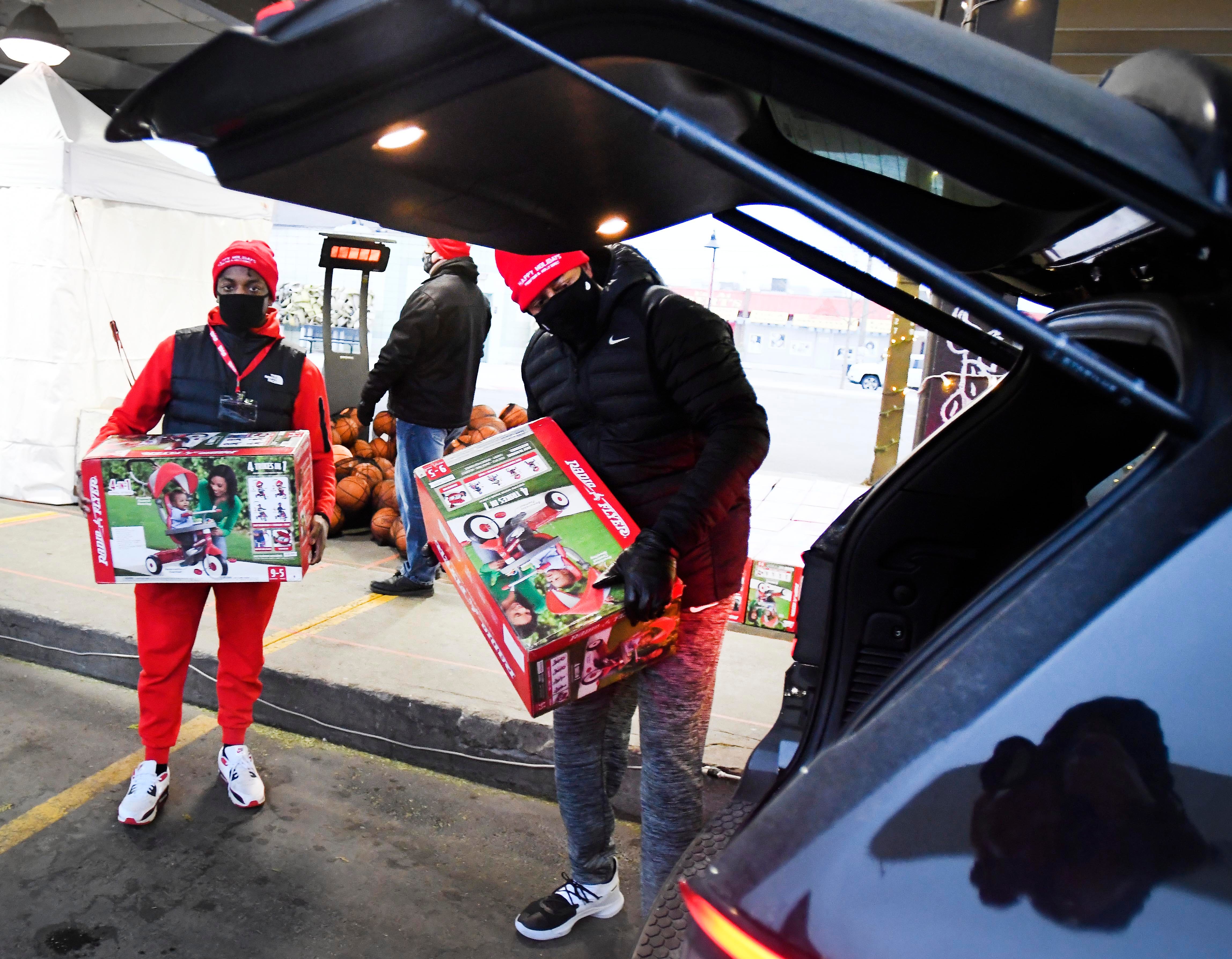 Piston employee volunteer Cedric Colbert and 12-year NBA veteran Earl Cureton load bicycles into the back of a car at a drive-through toy pickup in Eastern Market.