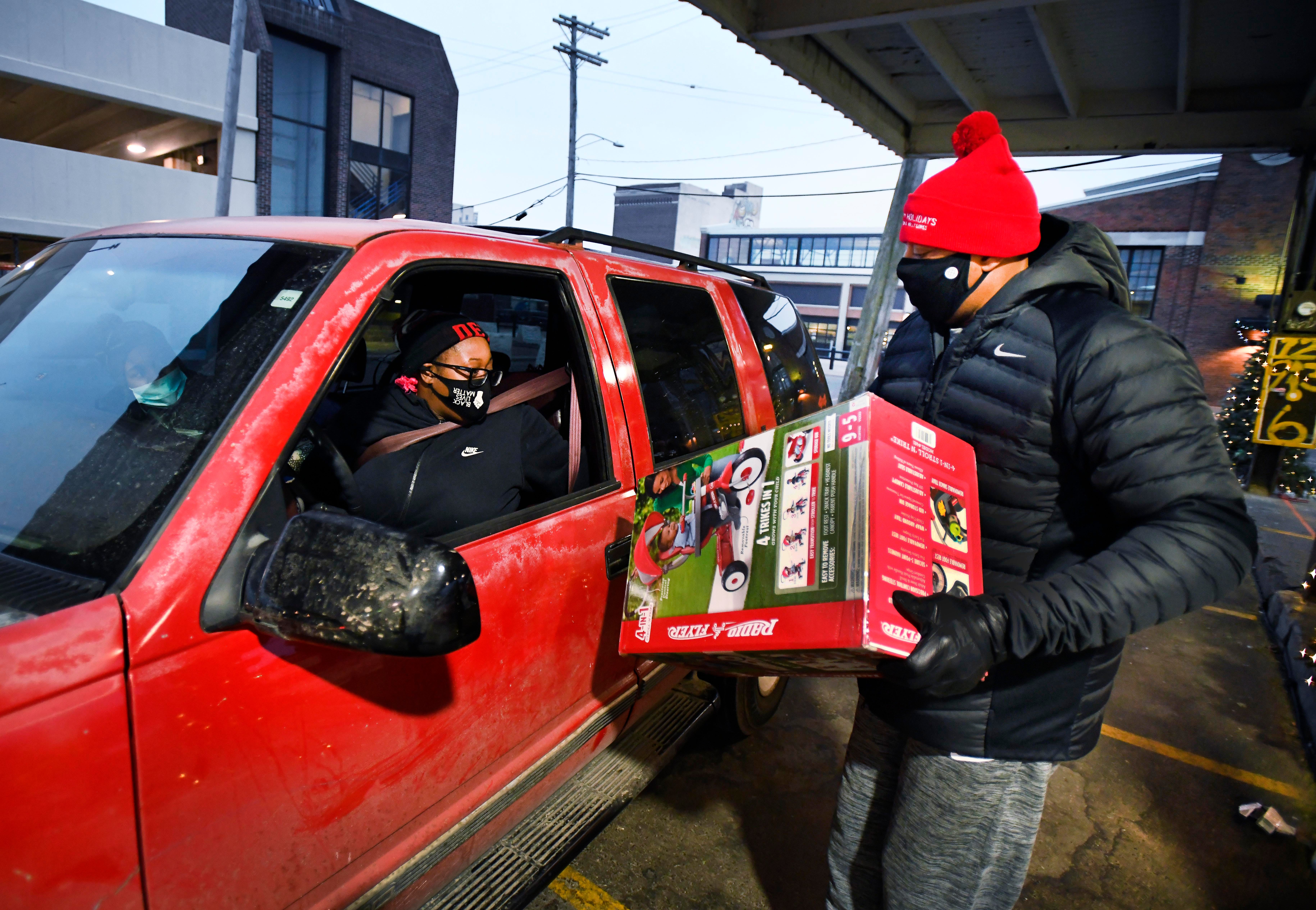 Former Piston Earl Cureton, right, delivers a bicycle to Dominque Broadnax as she makes her way through a drive-through toy pickup in Eastern Market in Detroit.