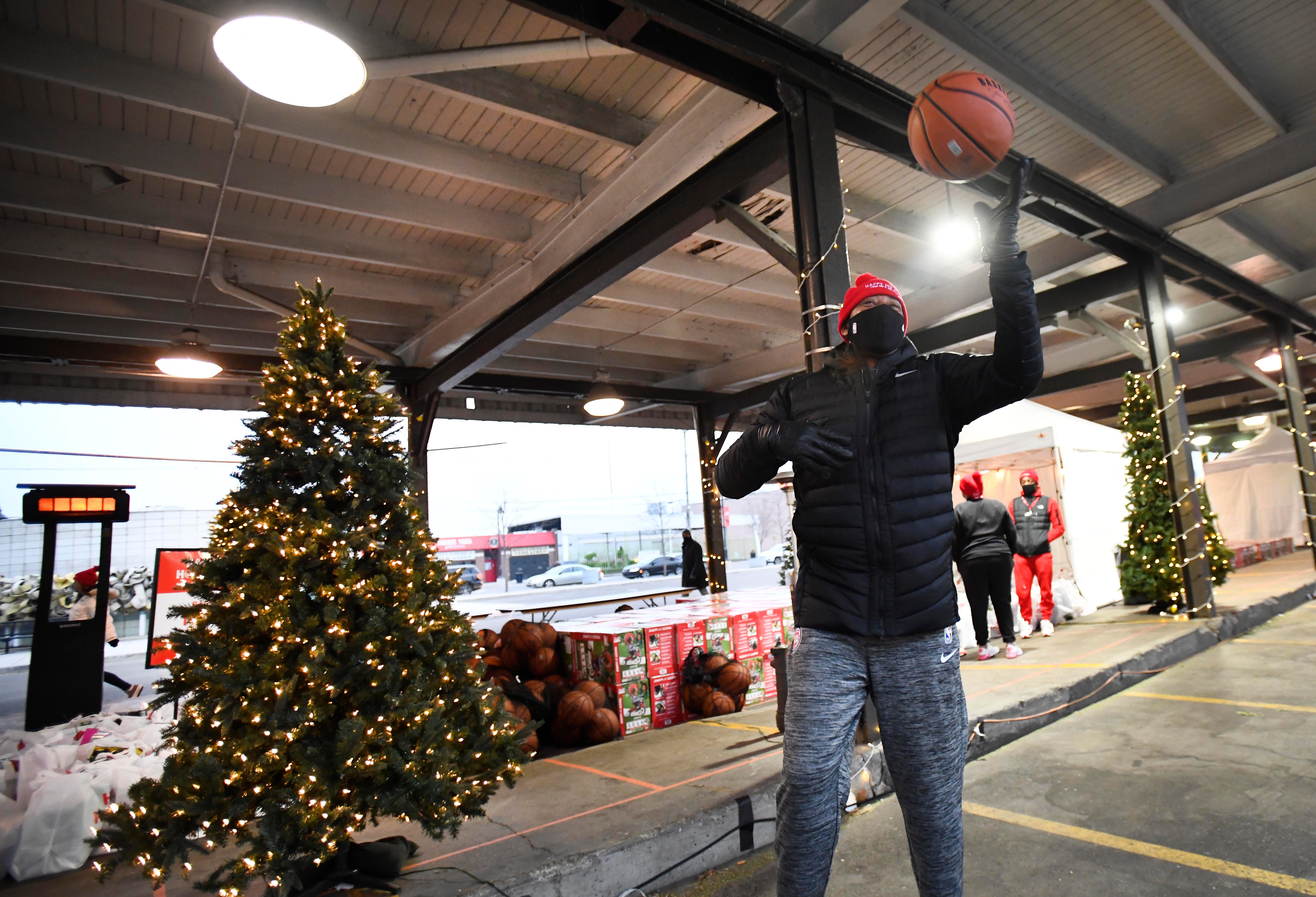 Really big kid, 12-year NBA veteran Earl “The Twirl” Cureton plays with a basketball waiting for the next car to pull up at a drive-through toy pickup in Eastern Market.