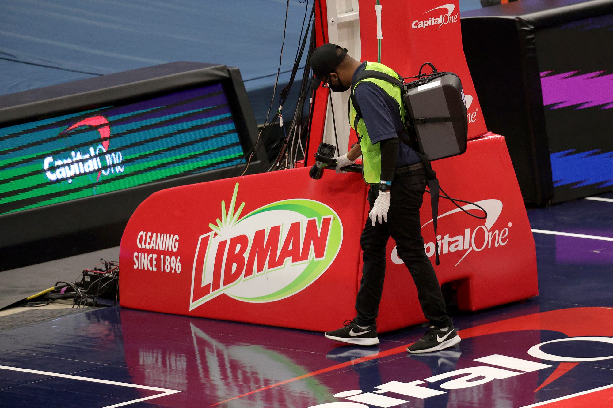 A worker disinfects the basket before the start of a preseason NBA basketball game between the Washington Wizards and Detroit Pistons, Saturday, Dec. 19, 2020 in Washington.