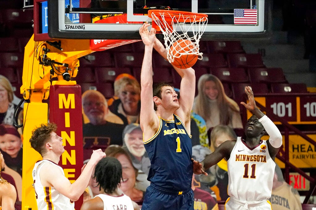 Michigan's Hunter Dickinson (1) dunks as Minnesota's Liam Robbins, left, Marcus Carr and Both Gach, right, watch during the first half.