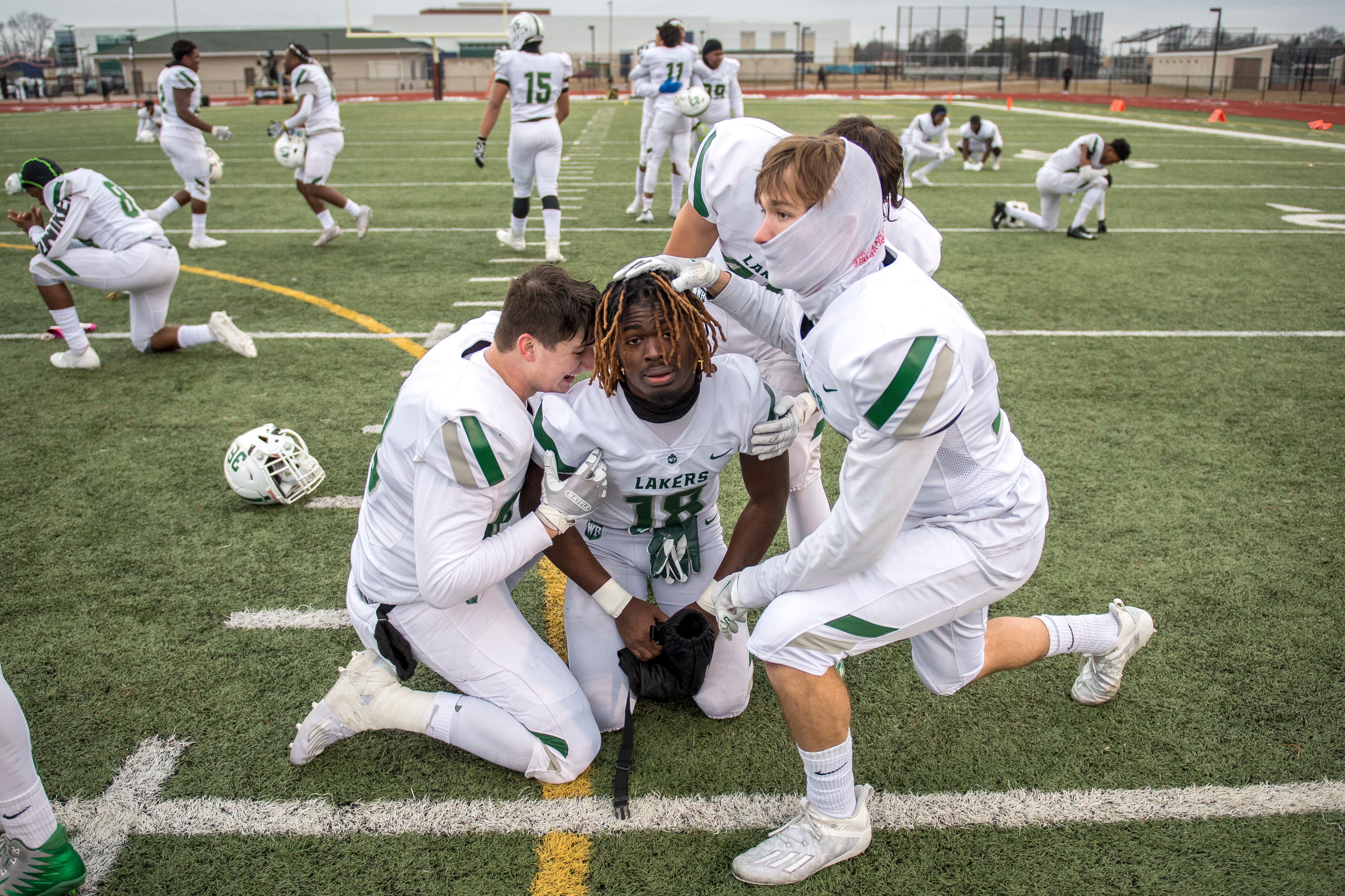 West Bloomfield sophomore Blake Nelson, left, junior Zaevion Marshall (18) and sophomore Trent Allison, right, embrace after defeating Belleville in double overtime, 35-34.