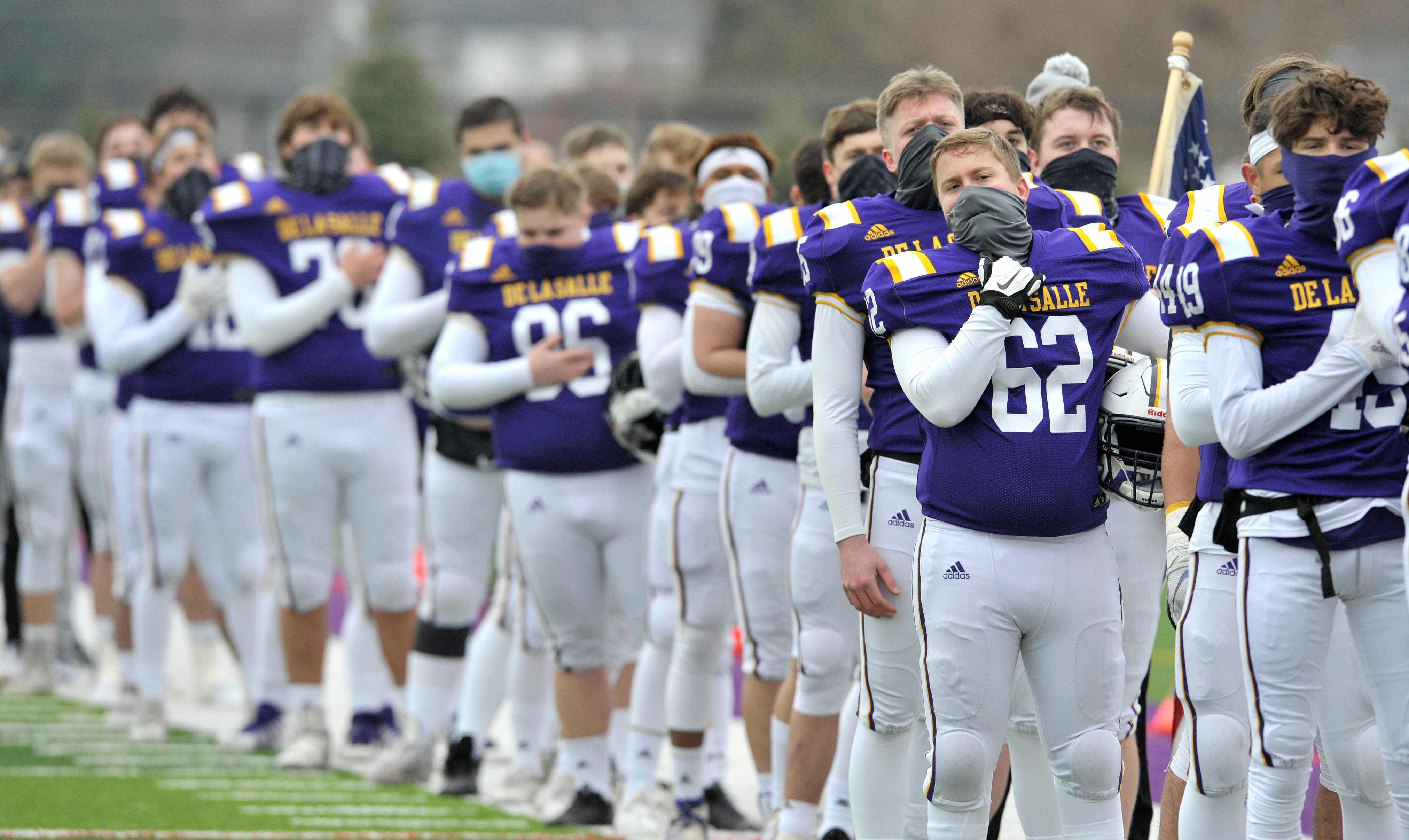 Members of the De La Salle football team stand during the playing the The National Anthem.