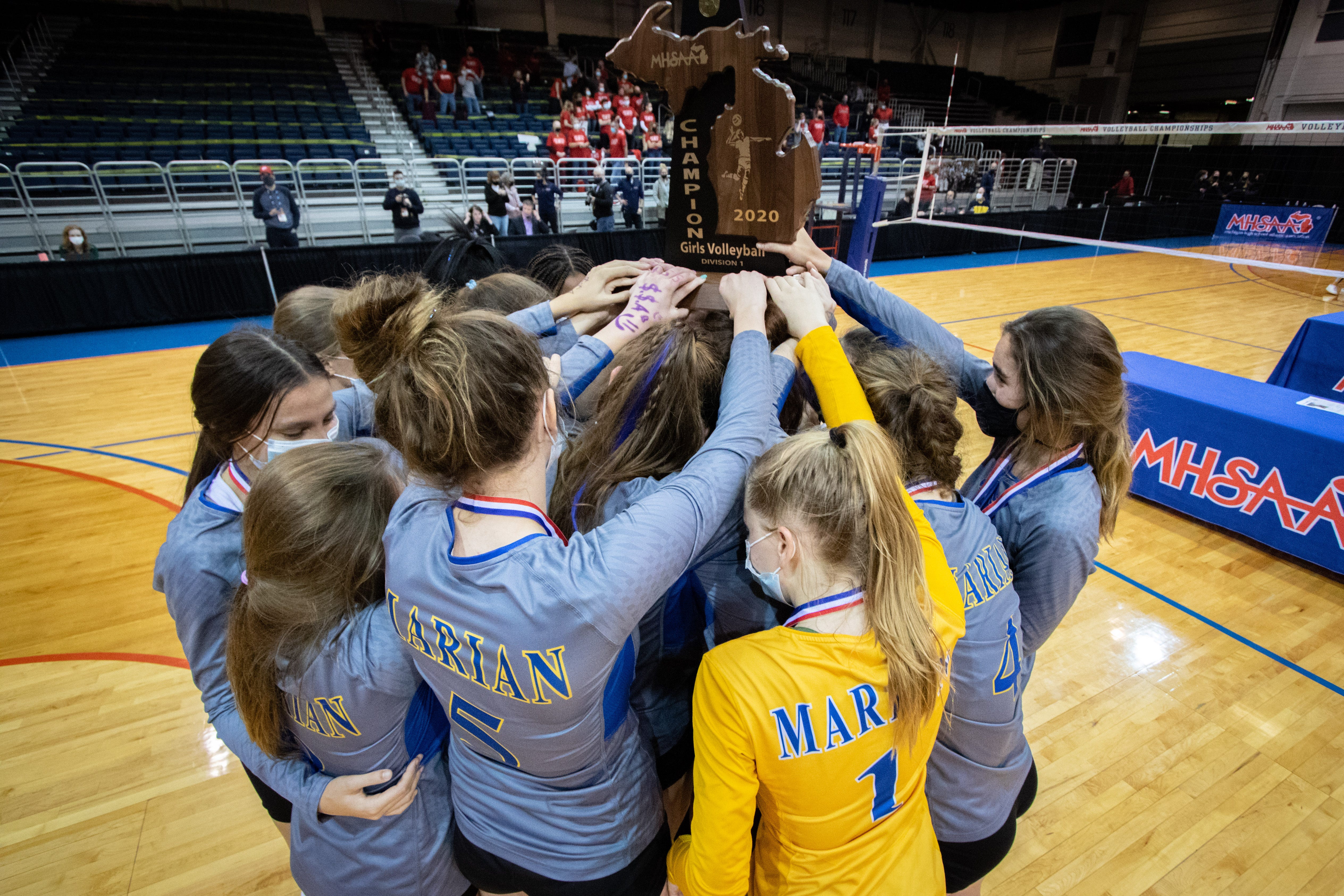 Marian players hoist the championship trophy together after defeating Lowell for the Division 1 state volleyball title in Battle Creek.