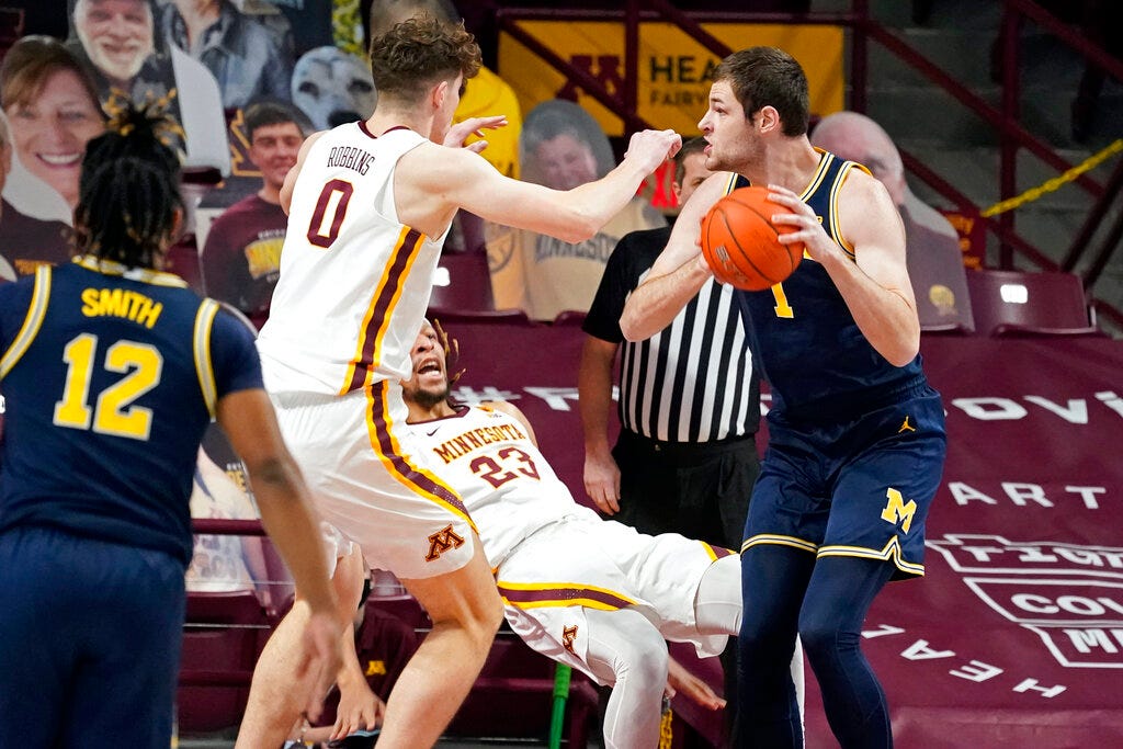 Minnesota's Brandon Johnson (23) falls as he defends against Michigan's Hunter Dickinson (1) during the first half an NCAA college basketball game, Saturday, Jan. 16, 2021, in Minneapolis. Minnesota won the game, 75-57