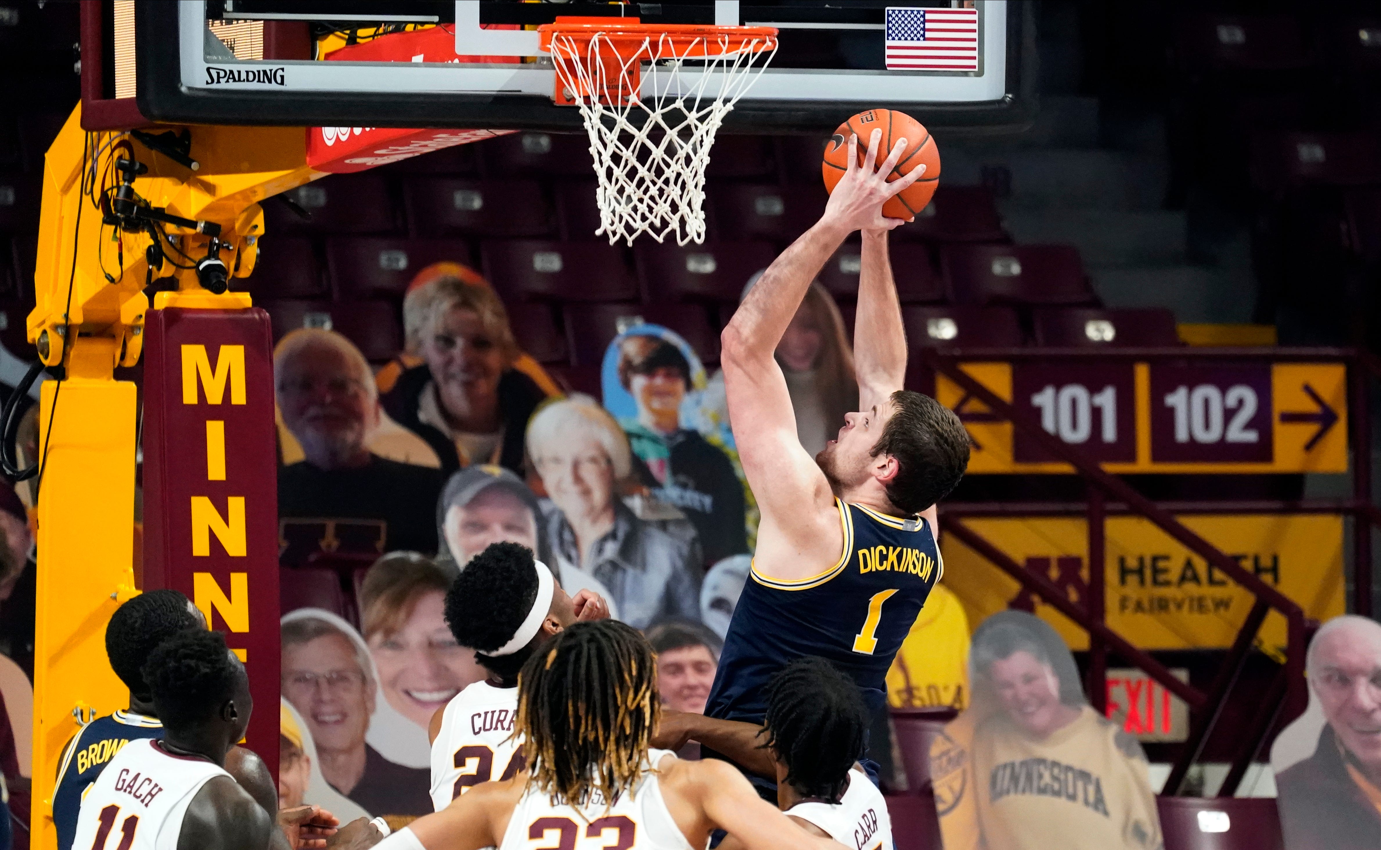Michigan's Hunter Dickinson (1) shoots and scores as four against Minnesota players watch in the first half.