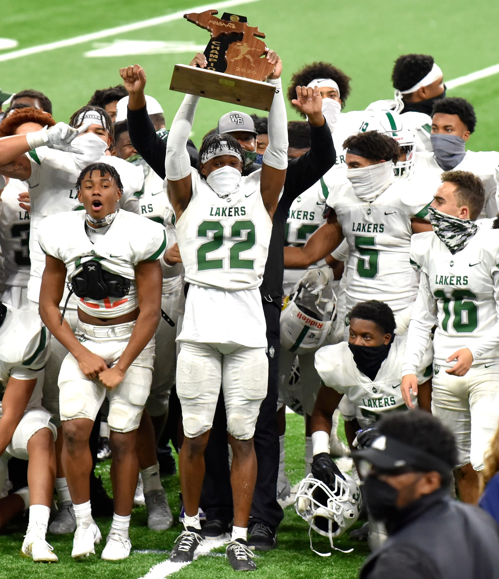 West Bloomfield's Maxwell Hairston (22) holds up his team's championship trophy.