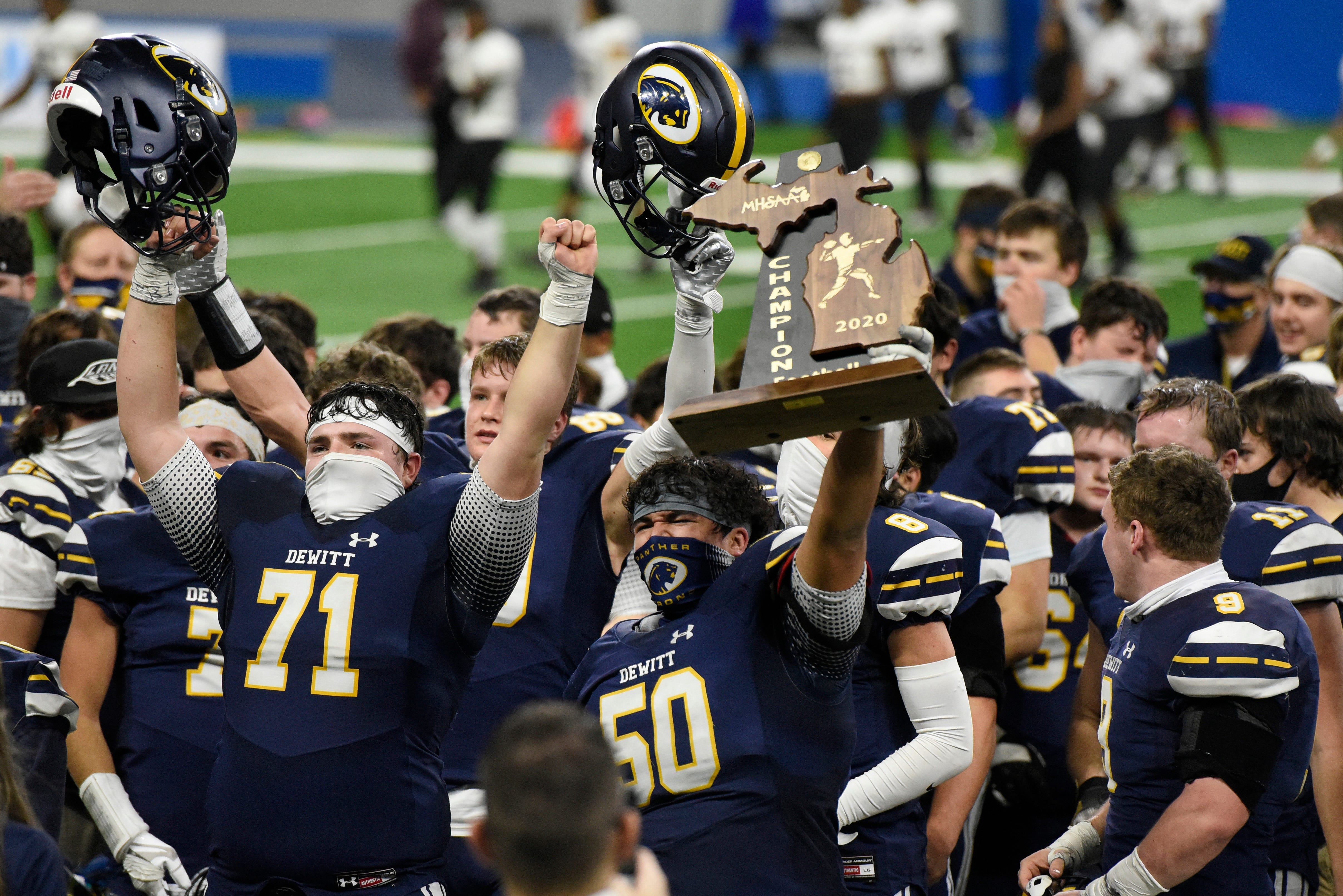 DeWitt lineman Conner Pochert (50) holds up the Division 3 championship trophy as his team celebrates defeating River Rouge 40-30.