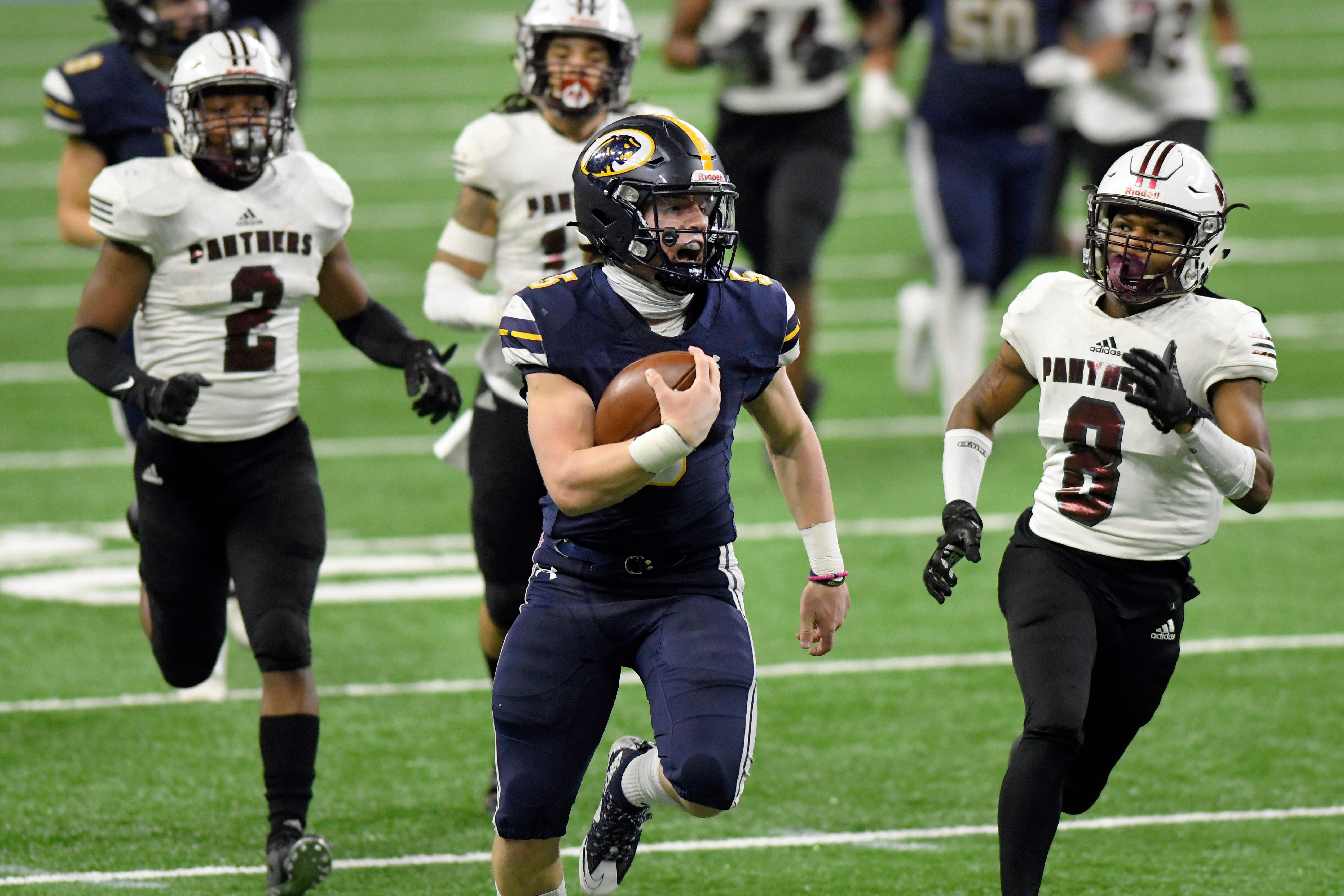 DeWitt quarterback Tyler Holtz, front, rushes for yardage as he is chased by River Rouge defenders, left, Markel Guilford, James Long, and Leamon Jones in the second quarter of a Division 3 football final held at Ford Field in Detroit, Saturday, Jan. 23, 2021.