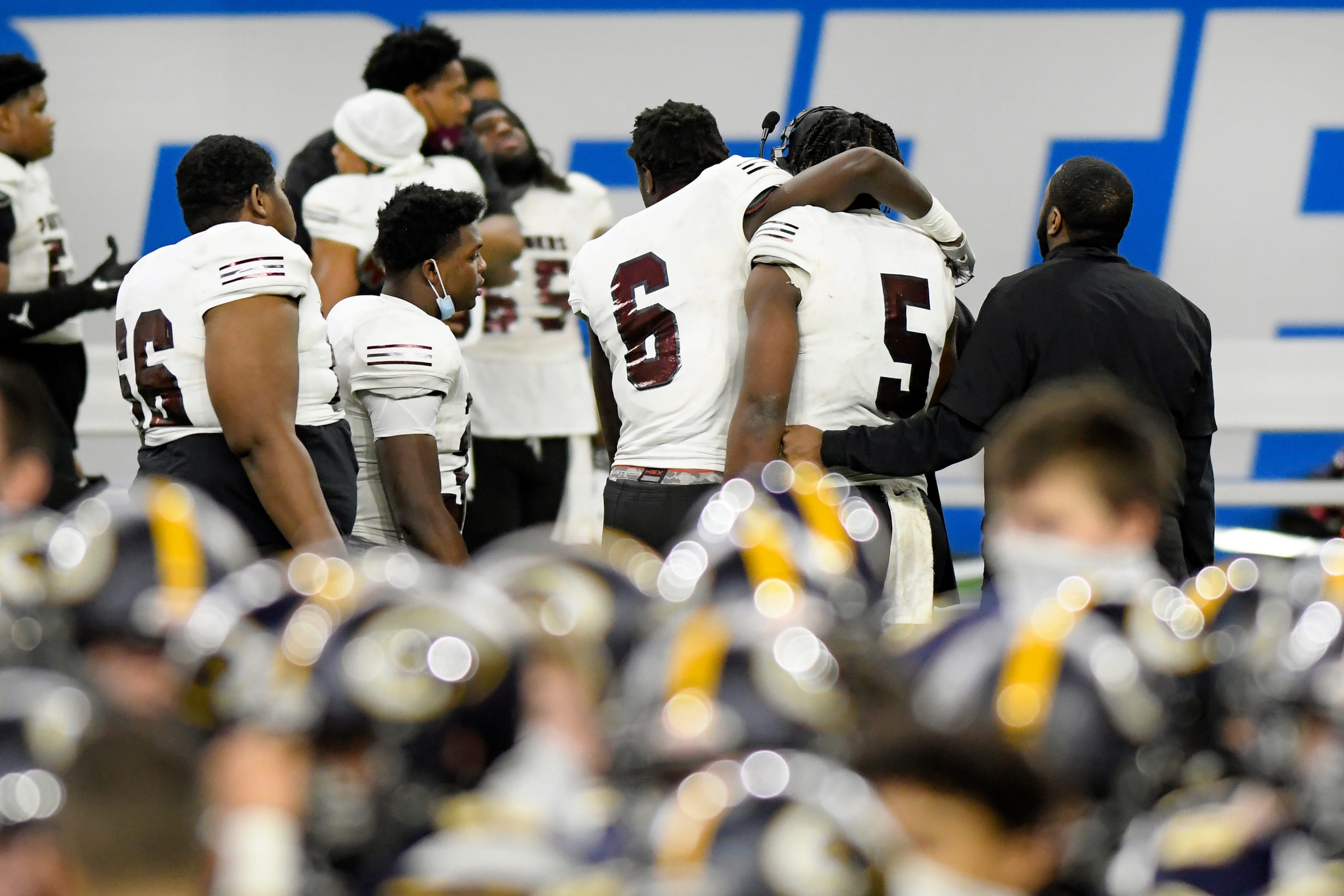 As the DeWitt football team celebrates in the foreground, River Rouge's Davon Jackson (6) consoles quarterback Mareyohn Hrabowski Saturday, Jan. 23, 2021, at Ford Field in Detroit. DeWitt defeated River Rouge 40-30.