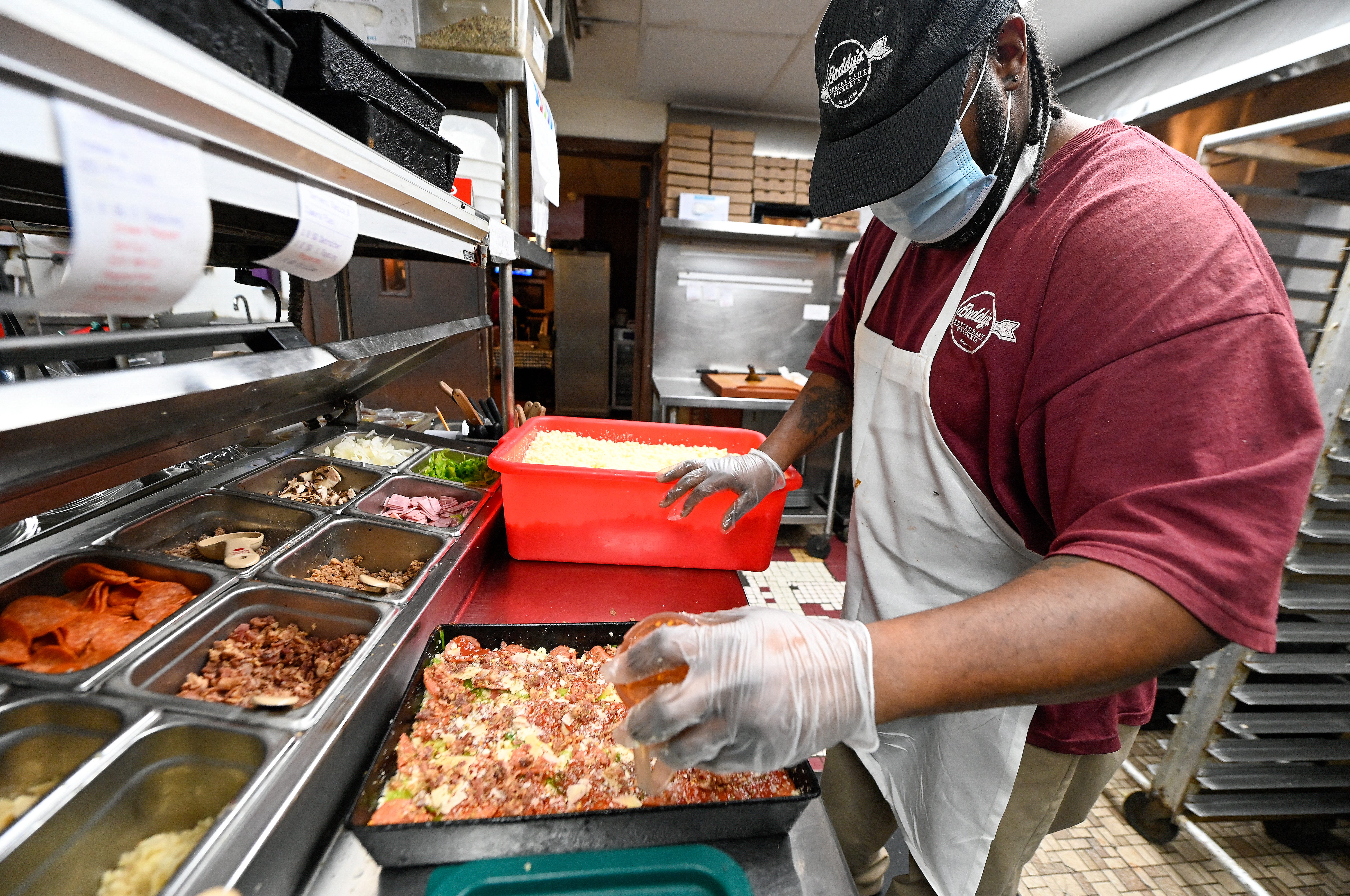 Pizza cook Garnett Thomas seasons a pizza at Buddy ' s Pizza in Detroit, Monday, February 15, 2021.