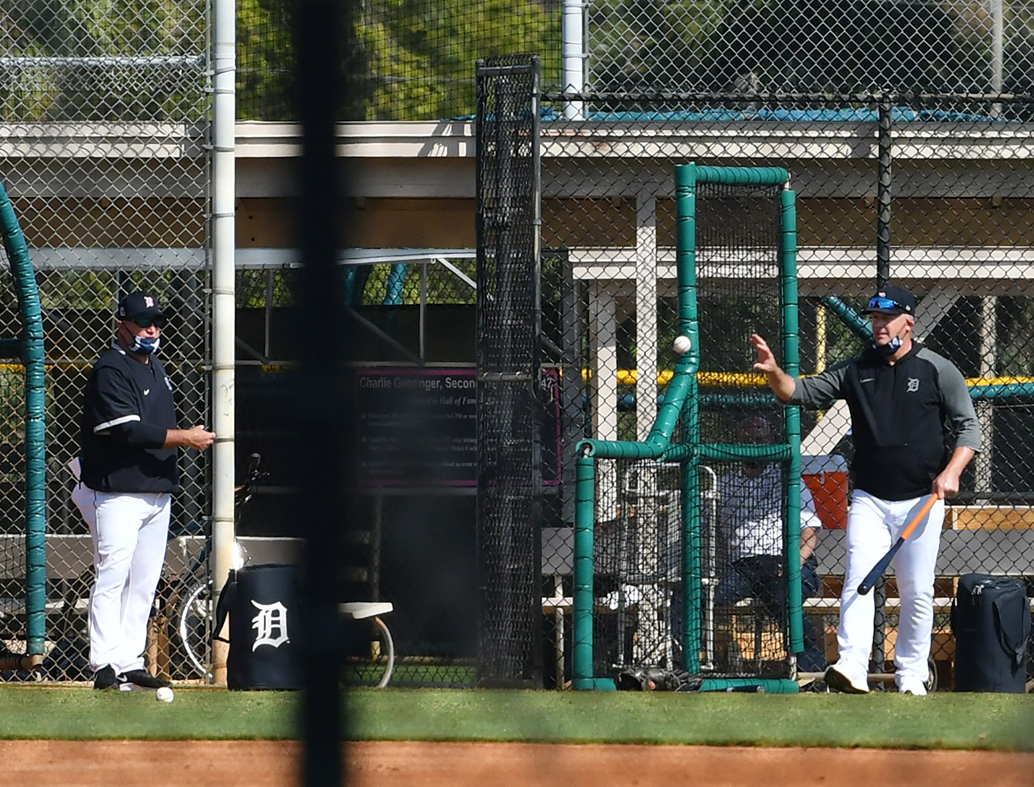 Tigers manager AJ Hinch, right, hits ground balls during infield practice.
