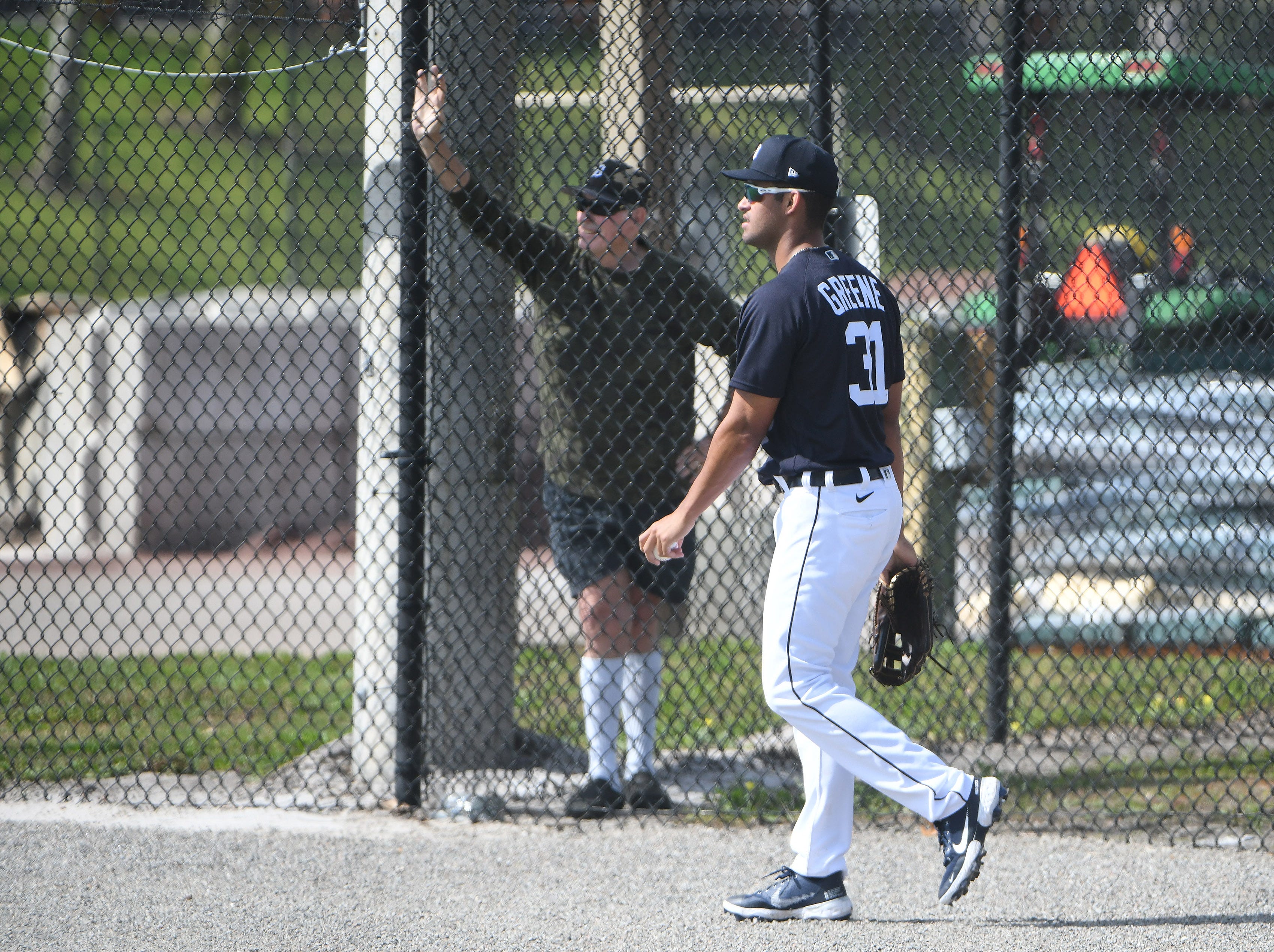 Tigers prospect Riley Greene walks past a fan at the outfield fence.