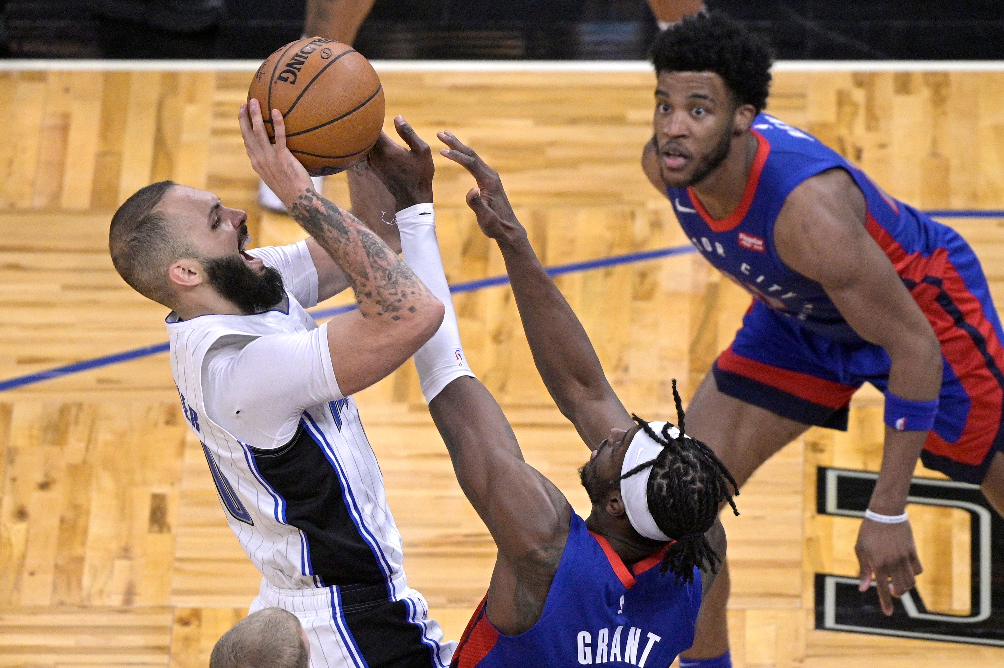 Orlando Magic guard Evan Fournier, left, is fouled by Detroit Pistons forward Jerami Grant, while going up for a shot, as forward Saddiq Bey, right, watches during the second half.
