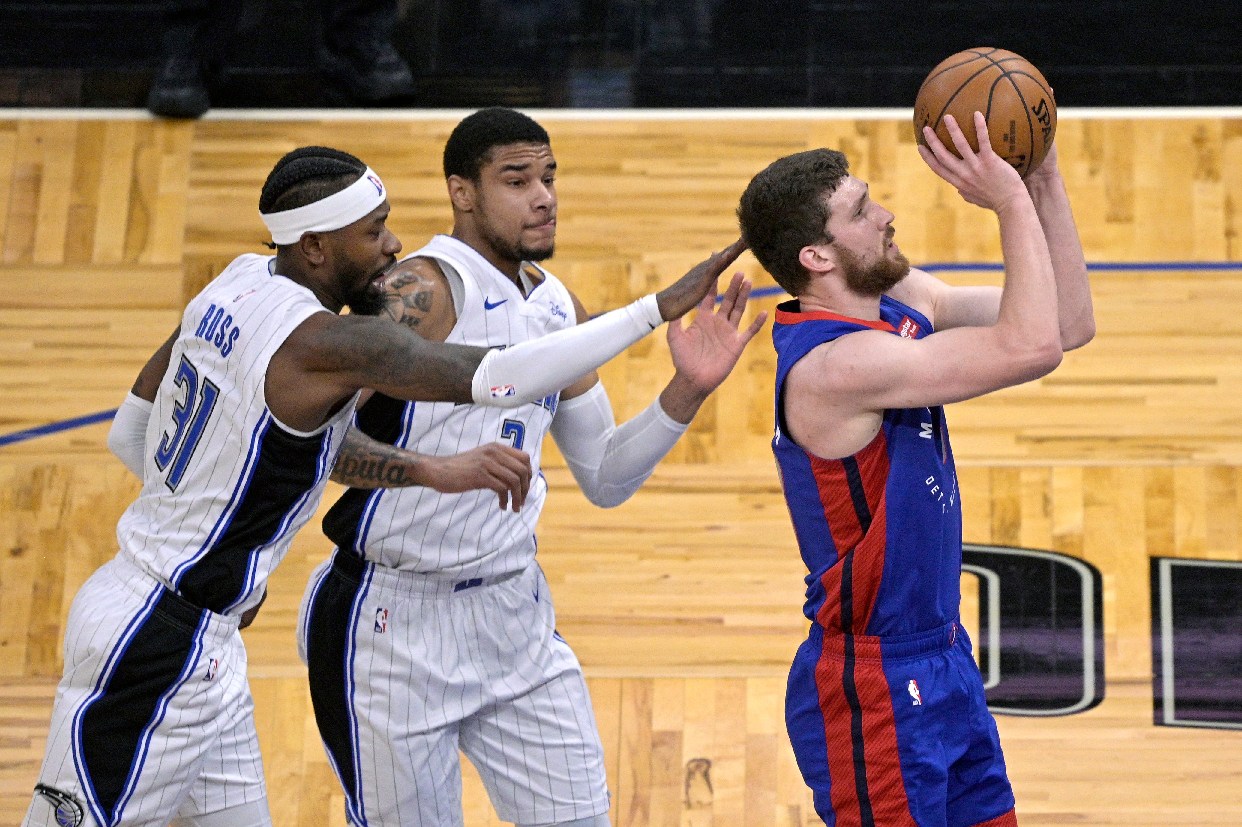 Detroit Pistons guard Svi Mykhailiuk, right, goes up for a shot in front of Orlando Magic guard Terrence Ross, left, and forward Chuma Okeke, center,  during the first half of an NBA basketball game.