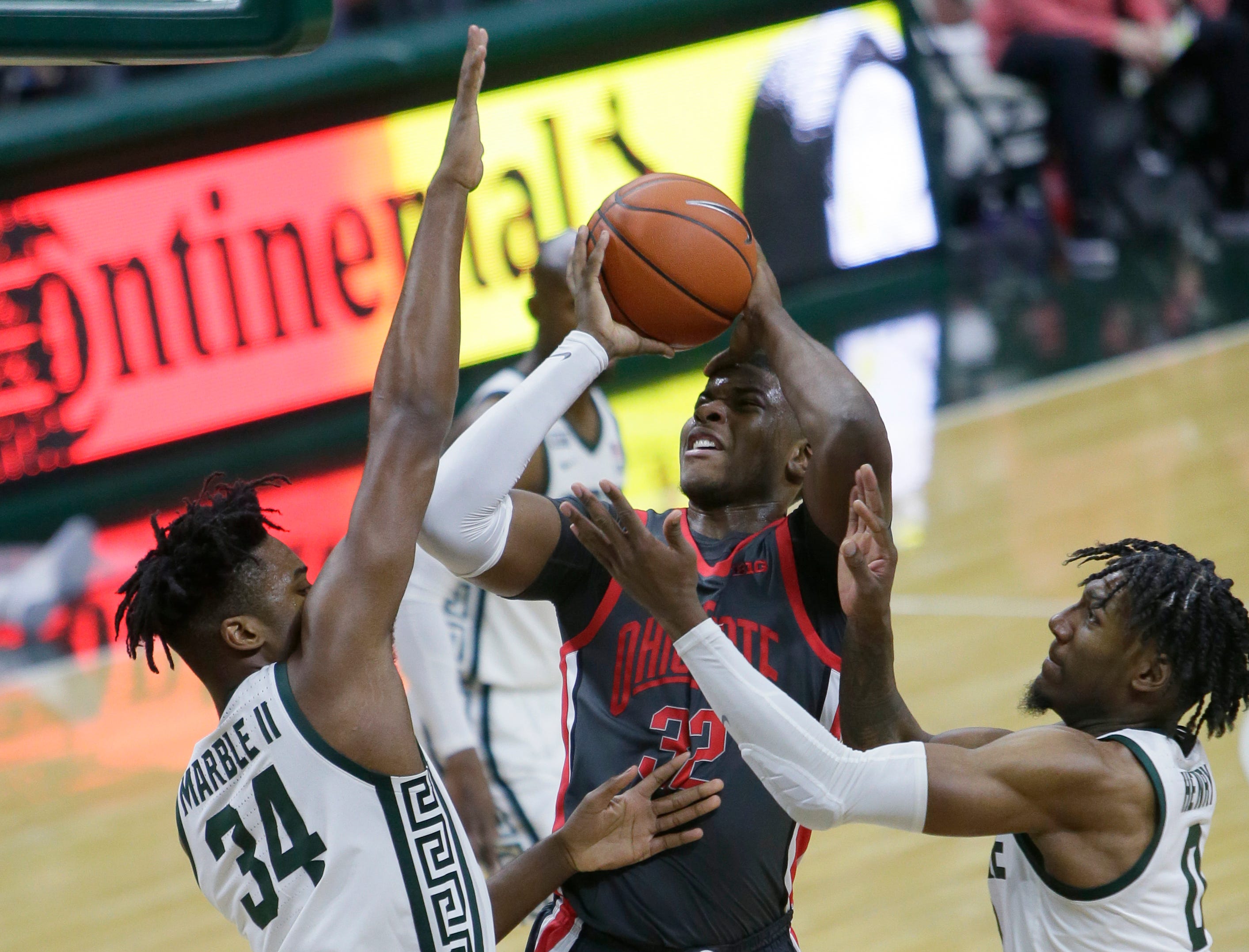 Ohio State forward E.J. Liddell (32) shoots against Michigan State forwards Julius Marble II (34) and Aaron Henry, right, during the first half of an NCAA college basketball game Thursday, Feb. 25, 2021, in East Lansing, Mich.