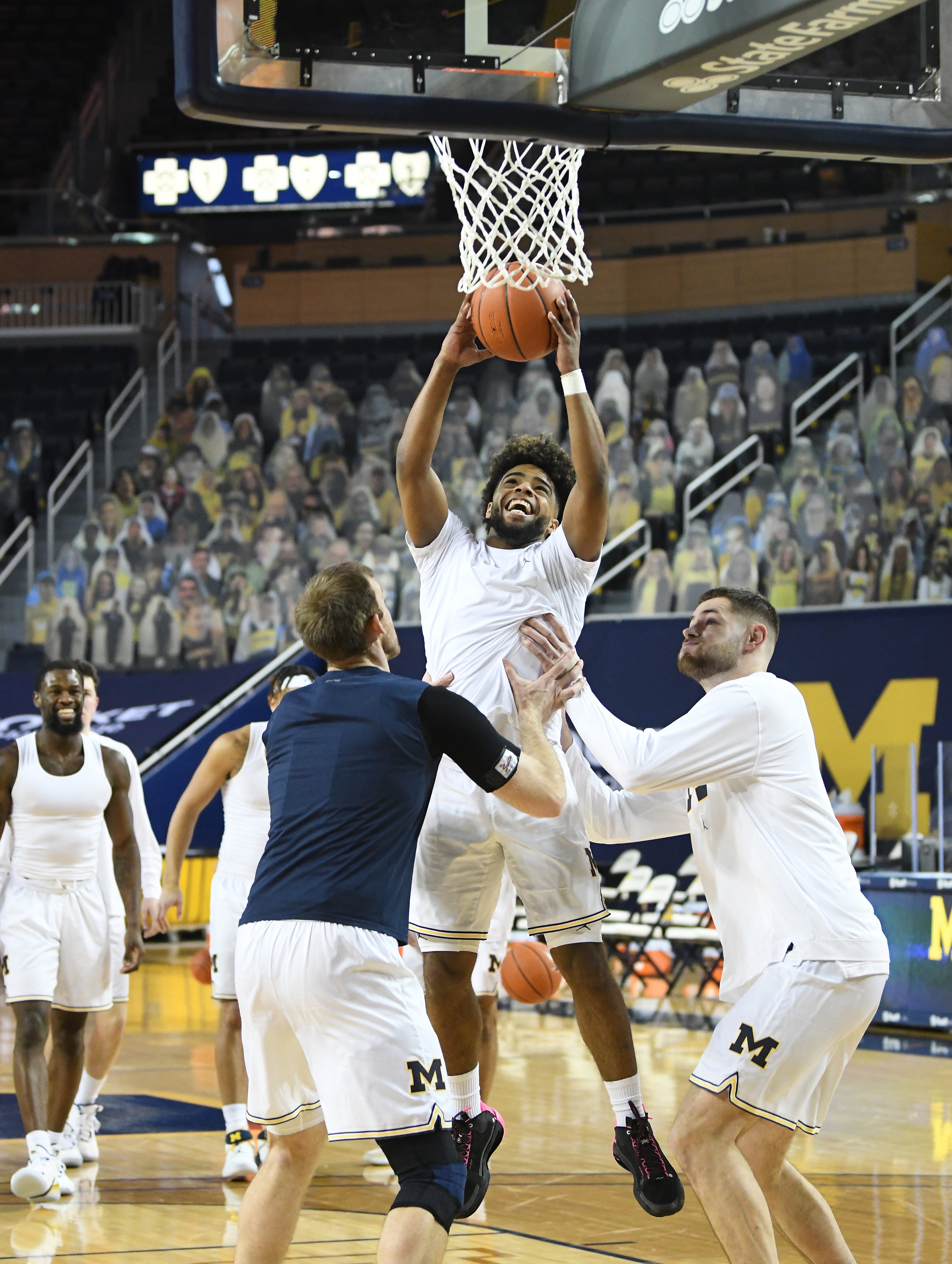 Michigan's Mike Davis dunks, with some help from teammates Austin Davis and Hunter Dickinson, at the end of warmups.