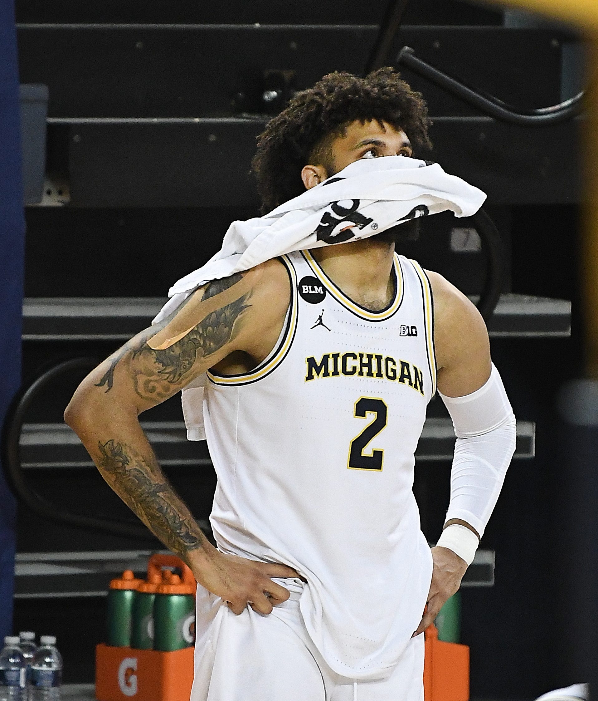 Michigan's Isaiah Livers covers his face with a towel with the other starters on the bench late in the second half.